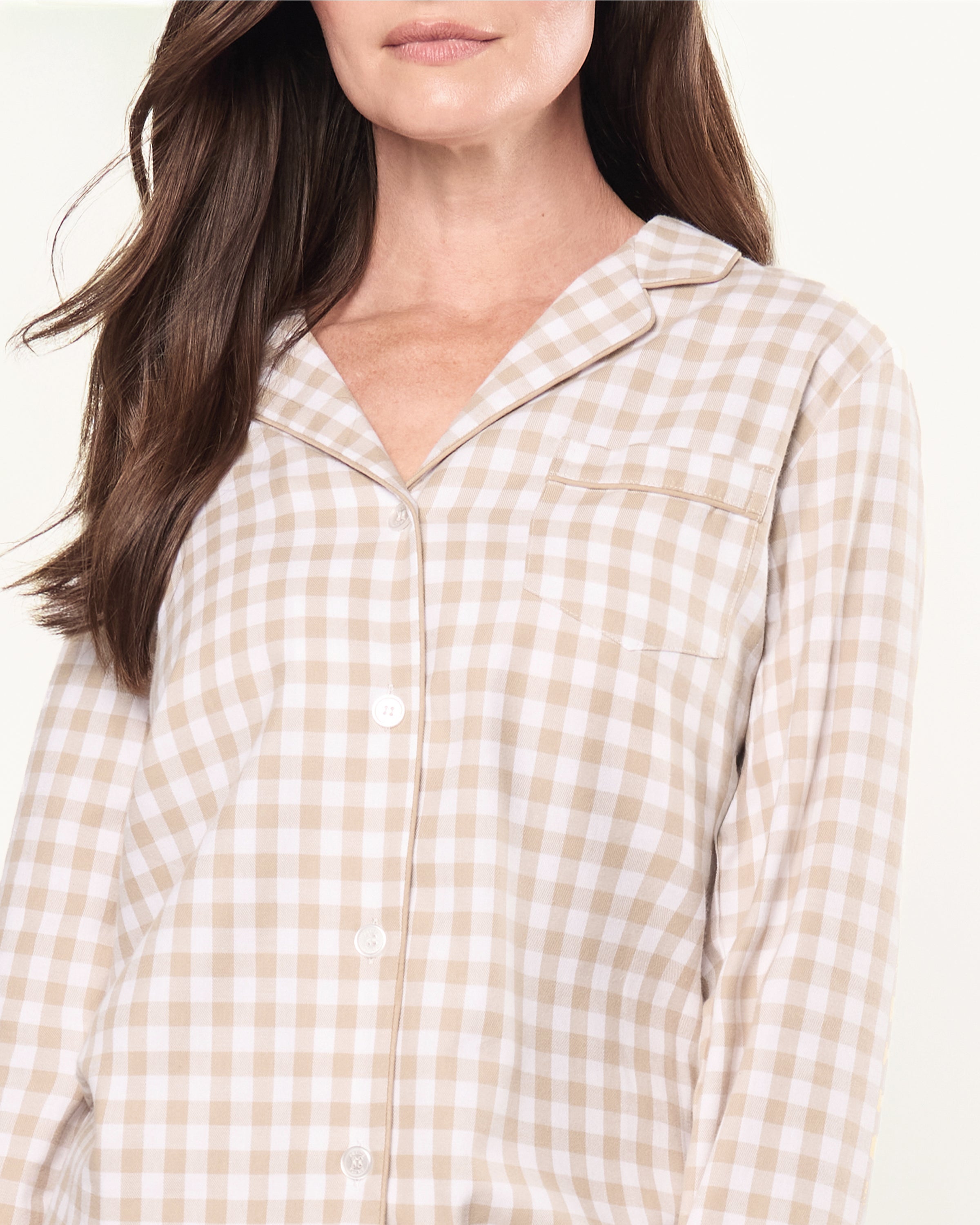 The Women's Twill Pajama Set in Camel Gingham features a beige and white check long-sleeve, button-up top with chest pocket and matching drawstring pants, displayed neatly on a white background.