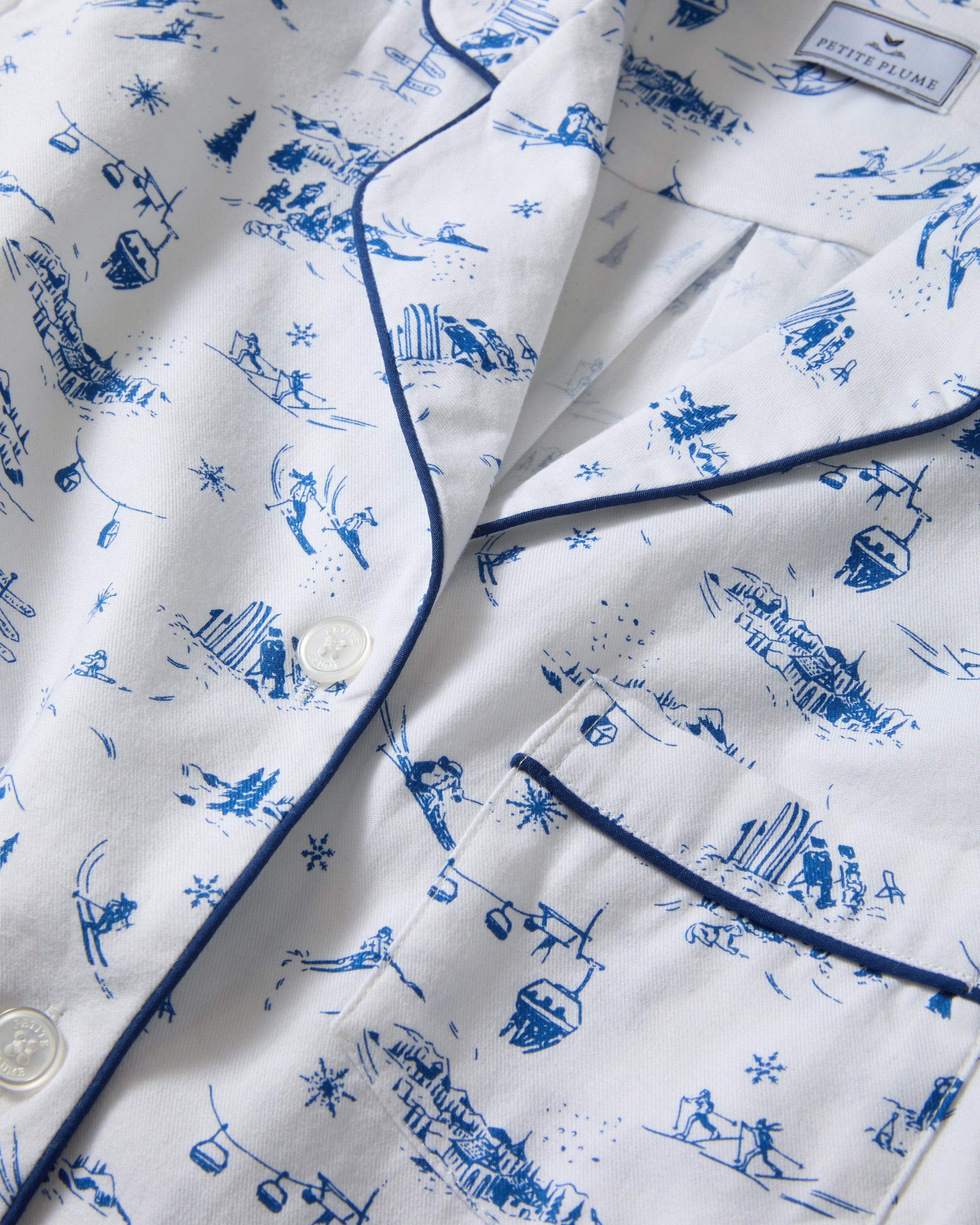 Women's Twill Pajama Set in Chalet Toile, featuring a white long-sleeve button-up shirt and matching pants with blue piping and a blue toile pattern, neatly displayed on a white background.