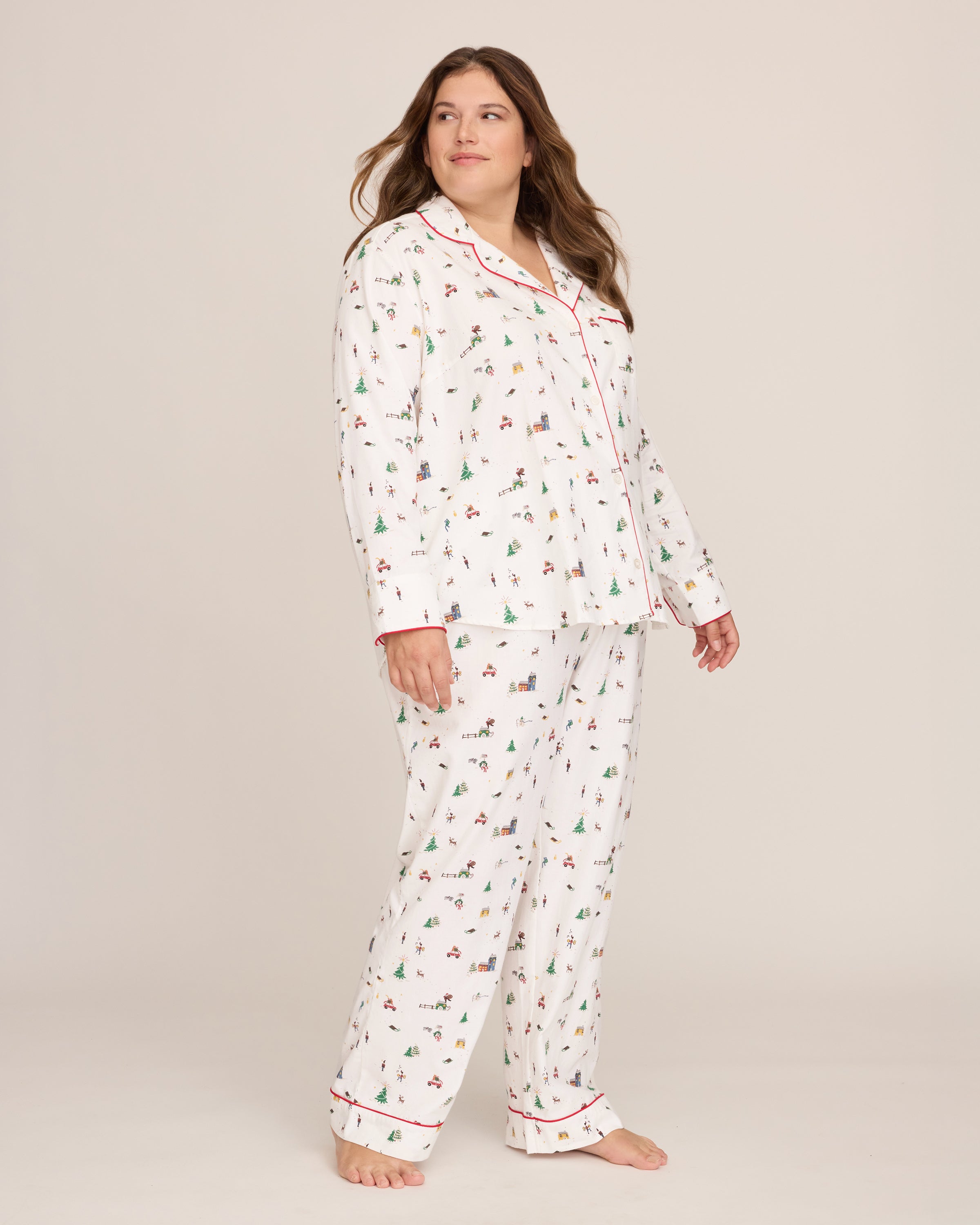 Women's Twill Pajama Set in Holiday Town: white pajama set with red piping, featuring festive prints of Christmas trees, cars, and skiers. Includes a long-sleeve button-up top with a pocket and matching drawstring pants.