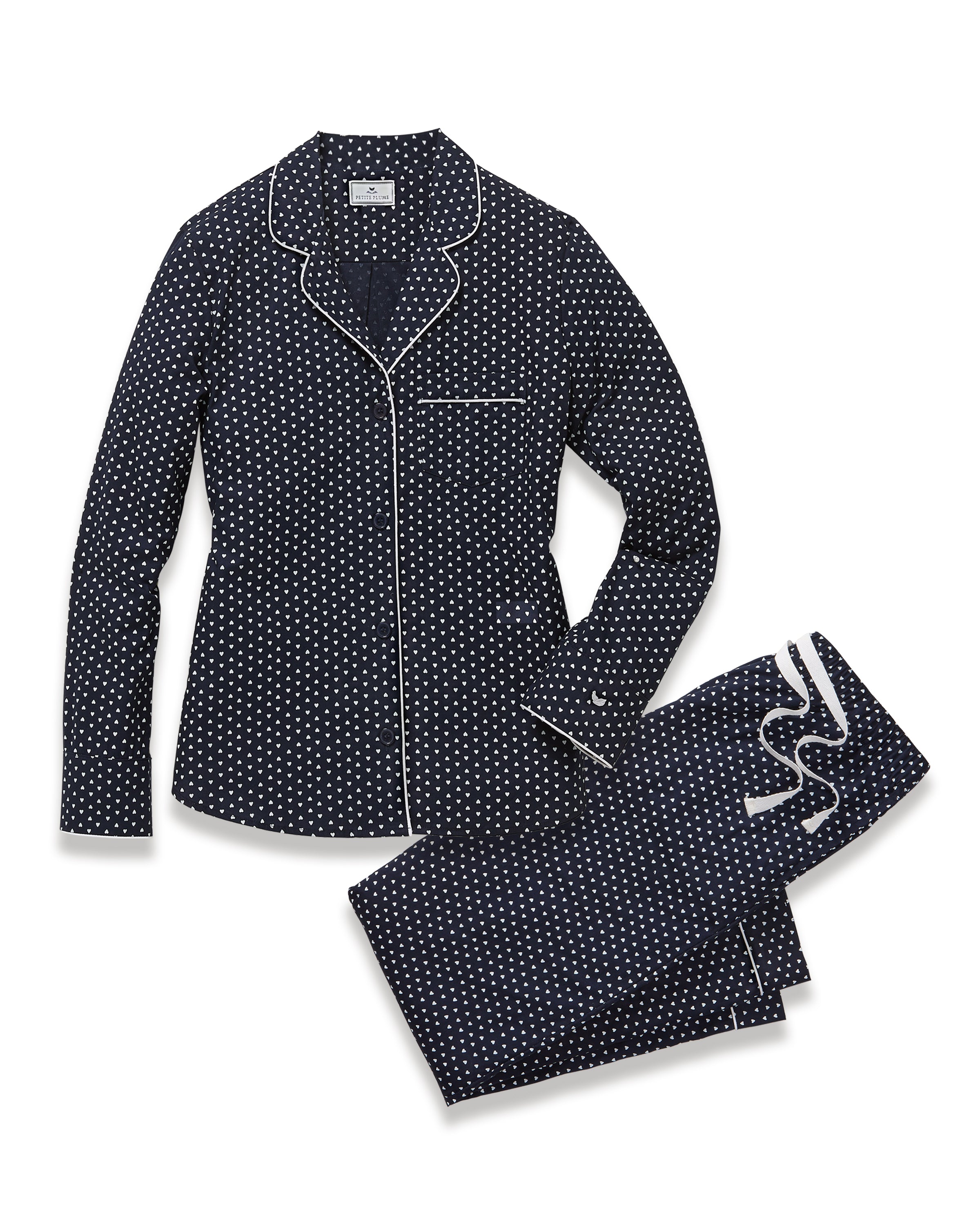The Women's Twill Pajama Set in Midnight Hearts features a navy blue, long-sleeve top with a collar, button-down front, white heart print, and white piping on the edges and pocket, paired with matching pants.
