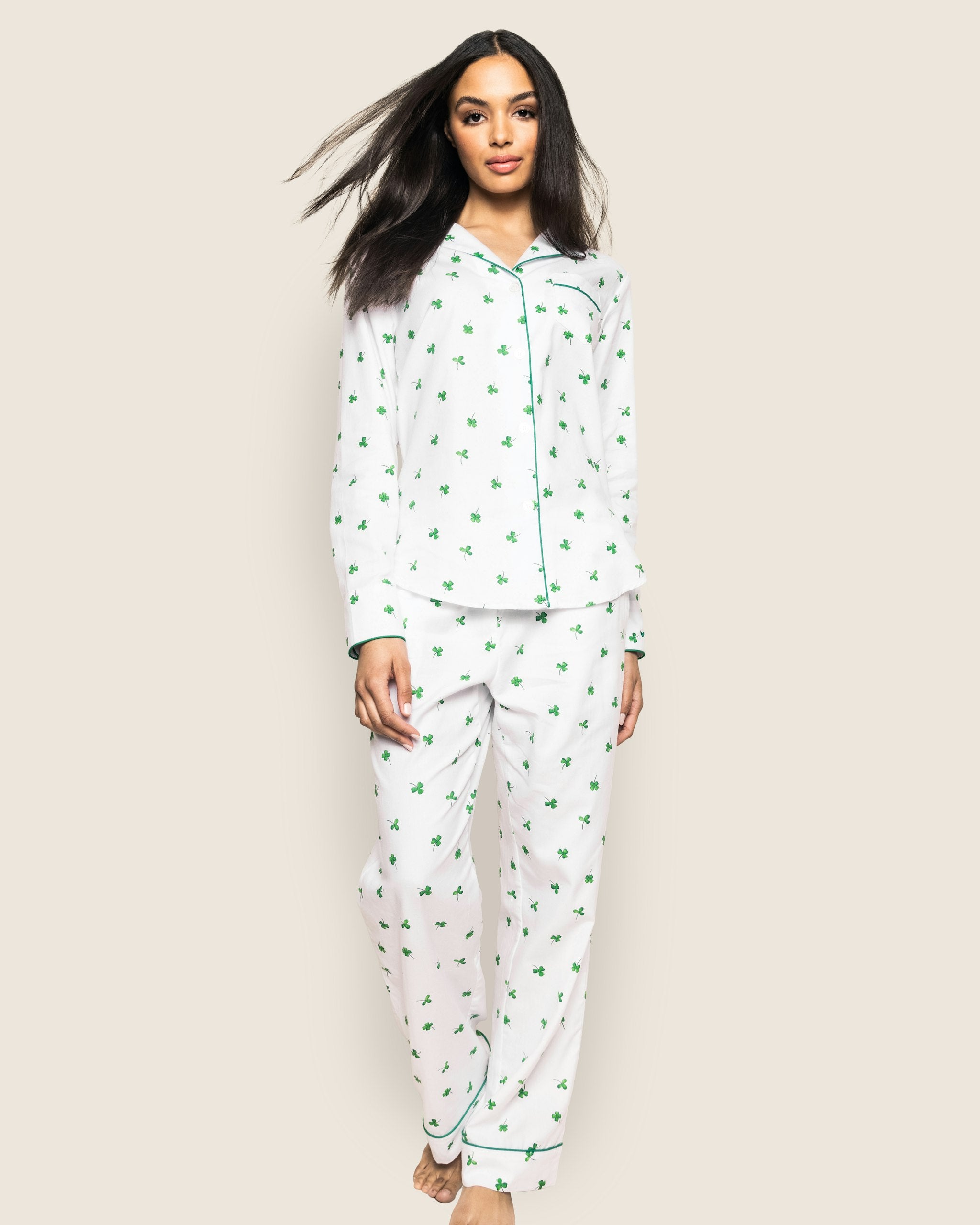 A women's pajama set with a white twill fabric featuring a green shamrock print, including a long-sleeved shirt and pants with a drawstring.