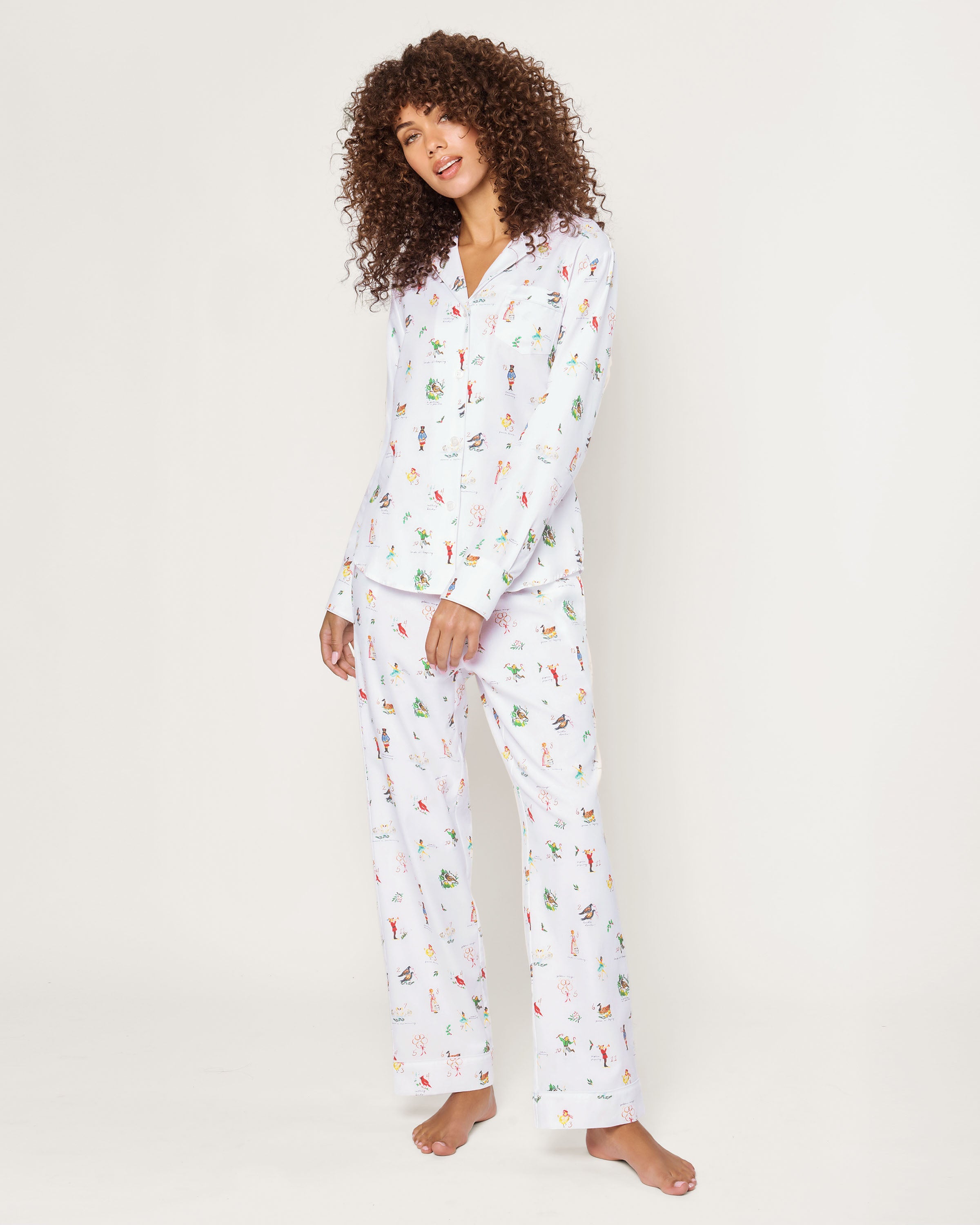 Women's Twill Pajama Set in 12 Days of Christmas features a white button-up long sleeve top and pants, adorned with a playful pattern of multicolored animals and palm trees.