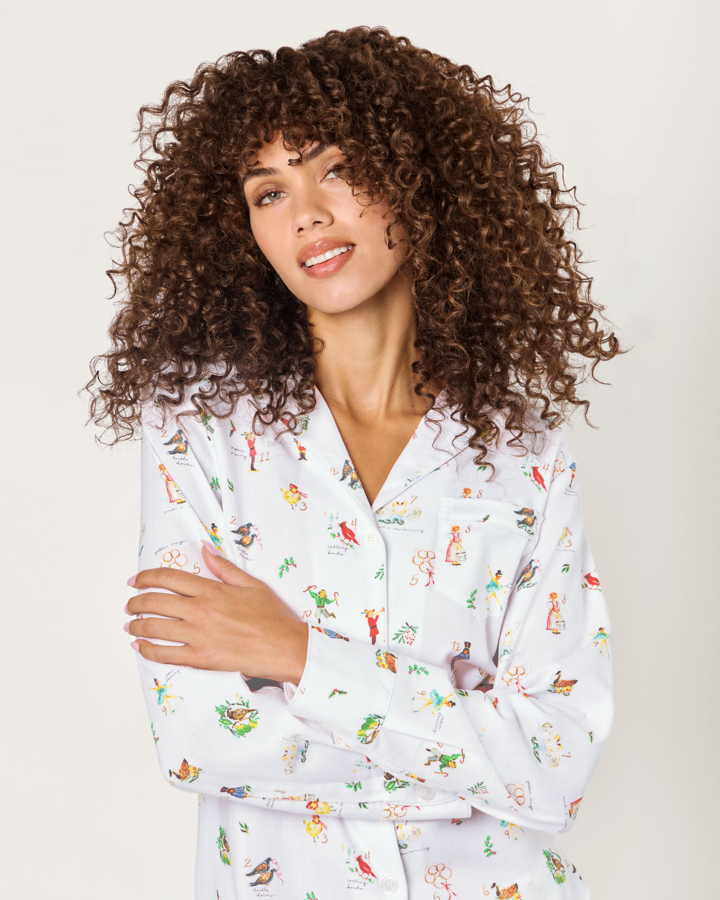 Women's Twill Pajama Set in 12 Days of Christmas features a white button-up long sleeve top and pants, adorned with a playful pattern of multicolored animals and palm trees.
