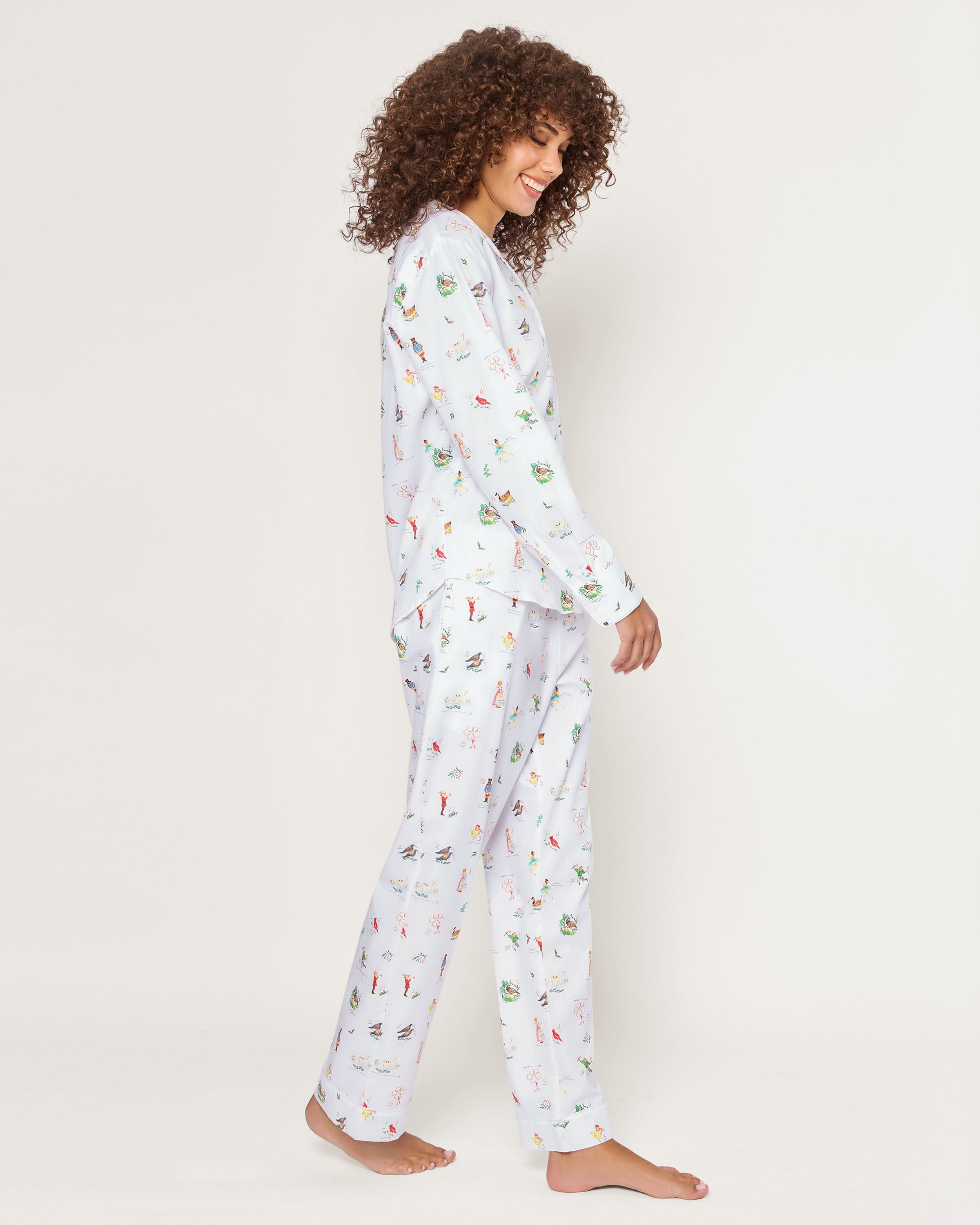 Women's Twill Pajama Set in 12 Days of Christmas features a white button-up long sleeve top and pants, adorned with a playful pattern of multicolored animals and palm trees.