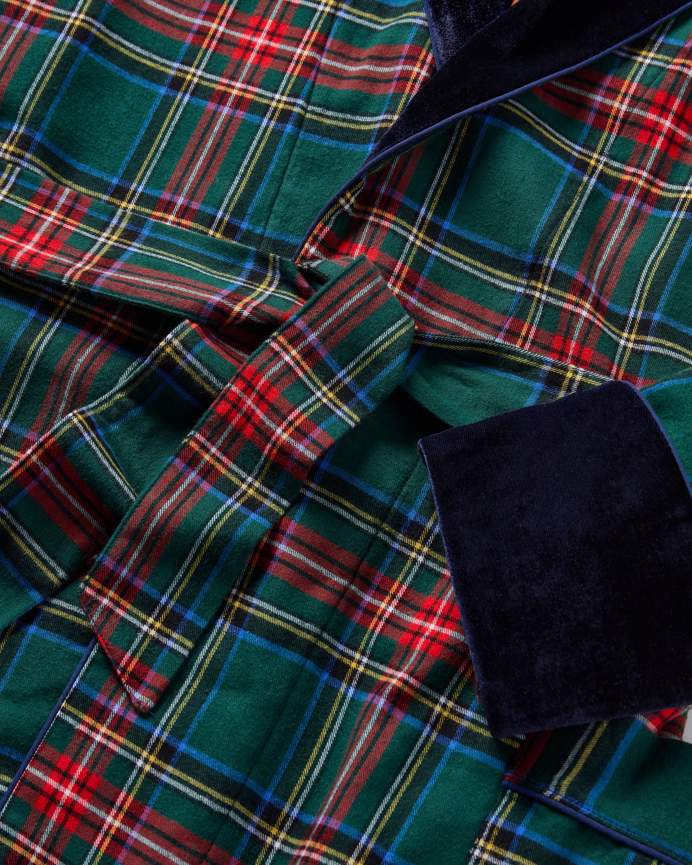 The Women's Brushed Twill Velvet Trim Robe in Kensington Tartan features green tartan with red and white stripes, a black velvet shawl collar and cuffs, a tie waist belt, and two large front pockets.