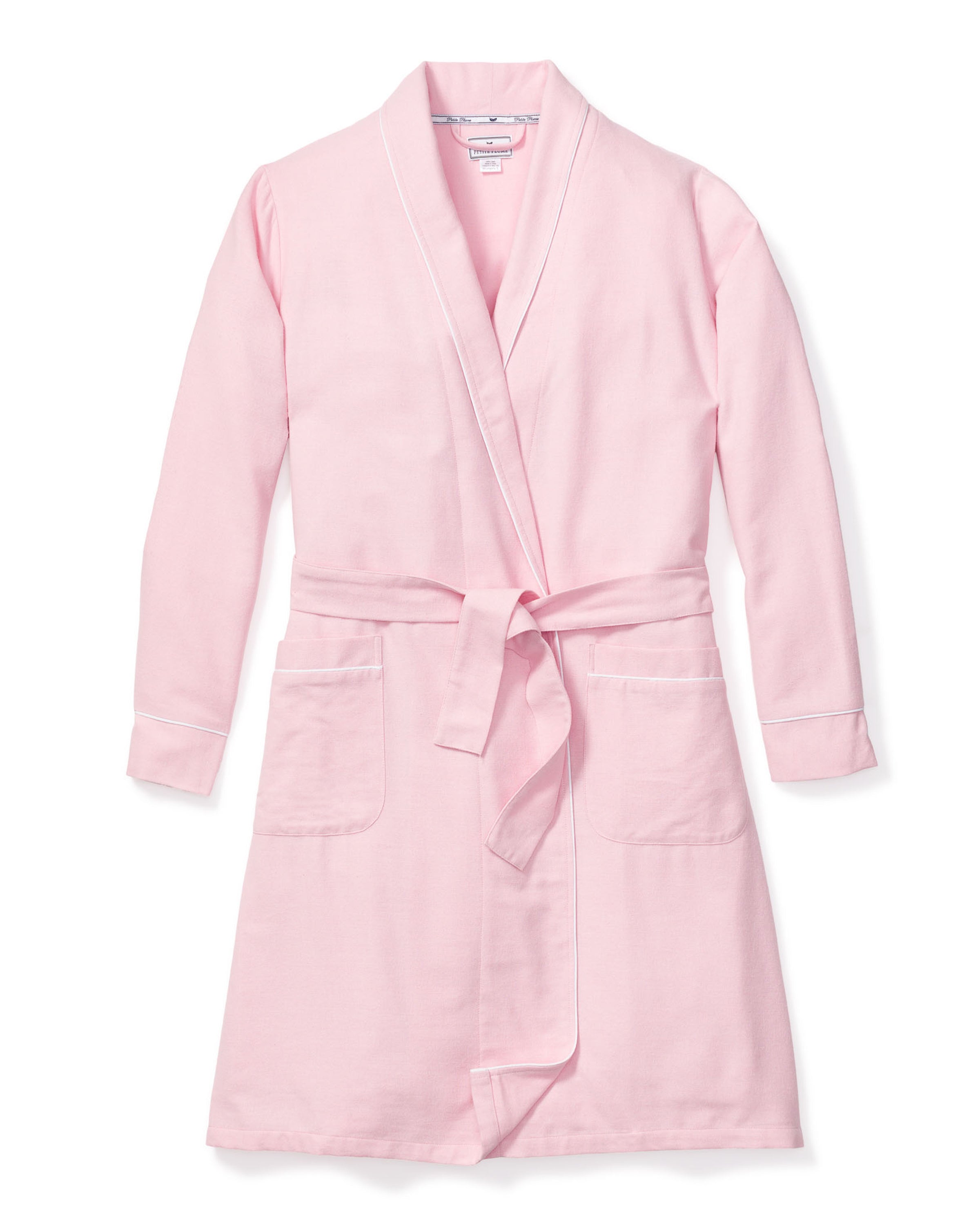 The Womens Flannel Robe in Pink by Petite Plume is a luxurious light pink bathrobe with long sleeves, two front pockets, a matching belt for the waist, and elegant white piping. Its crafted from high-quality cotton and laid flat against a white background for indulgent lounging.