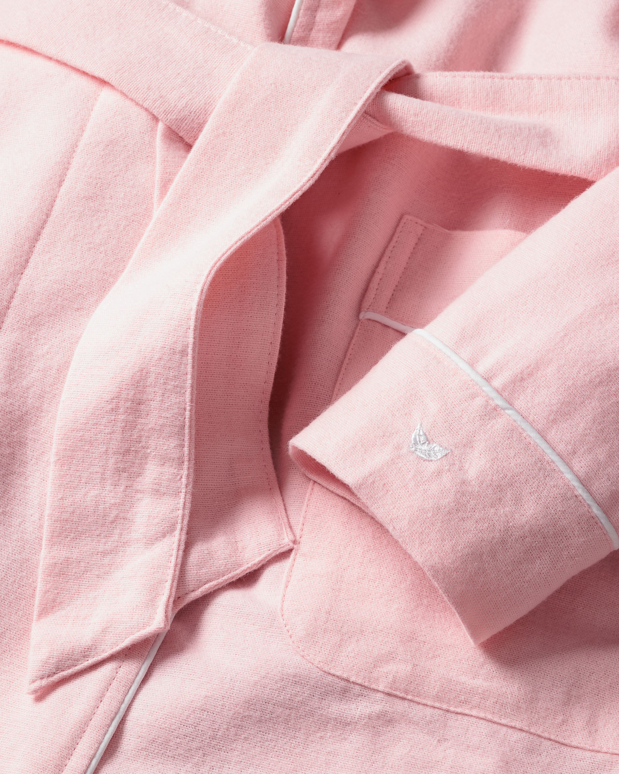 The Petite Plume Womens Flannel Robe in Pink is a luxurious 100% cotton sleepwear with a belt and pocket. It features white piping on the sleeves and an embroidered white butterfly motif.