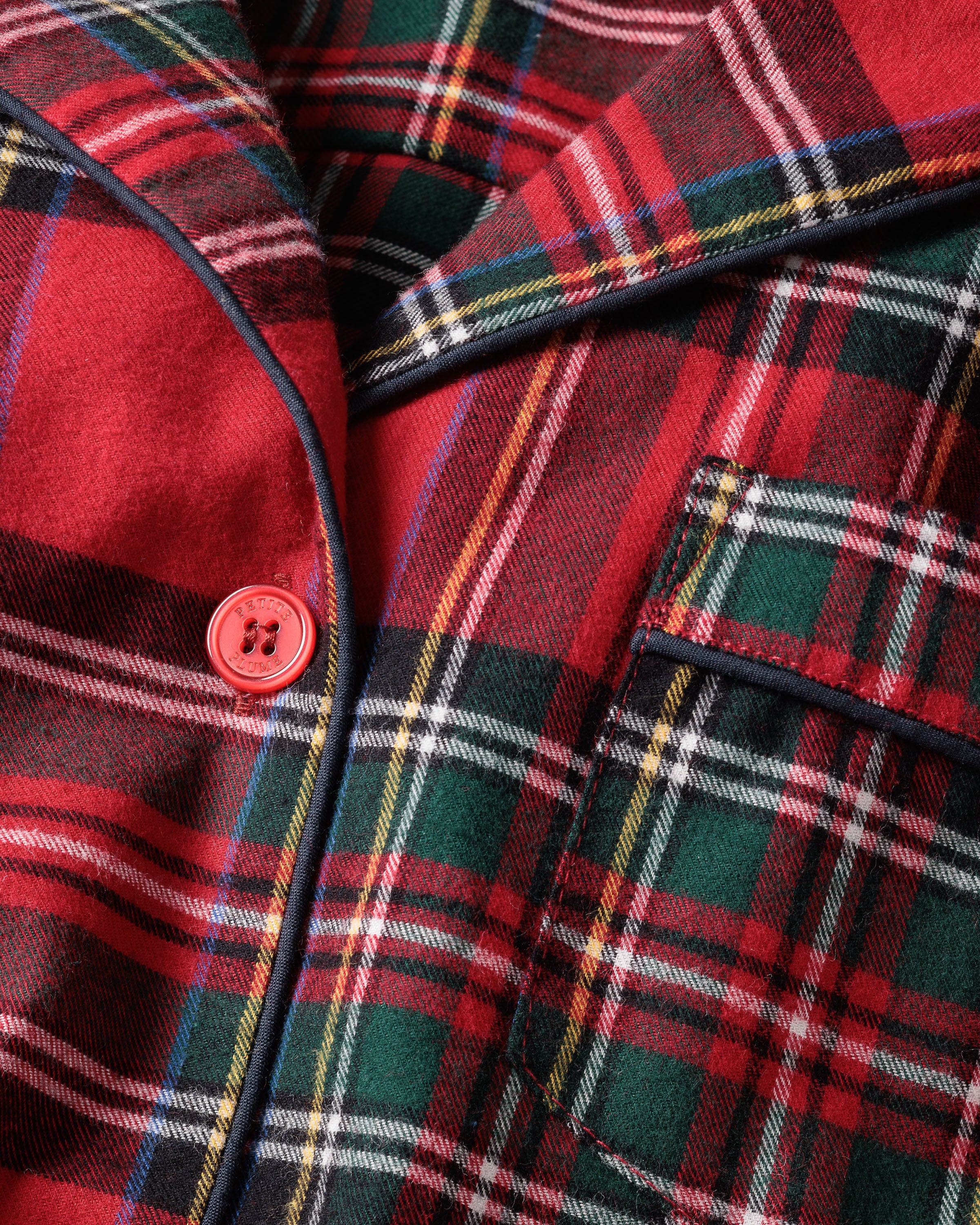 Close-up of Petite Plumes Womens Brushed Cotton Short Sleeve Short Set in Imperial Tartan, showcasing vibrant red, green, and white Scottish plaid. The finest quality cotton set features a red button and black piping, indicating it could be part of a jacket or shirt.