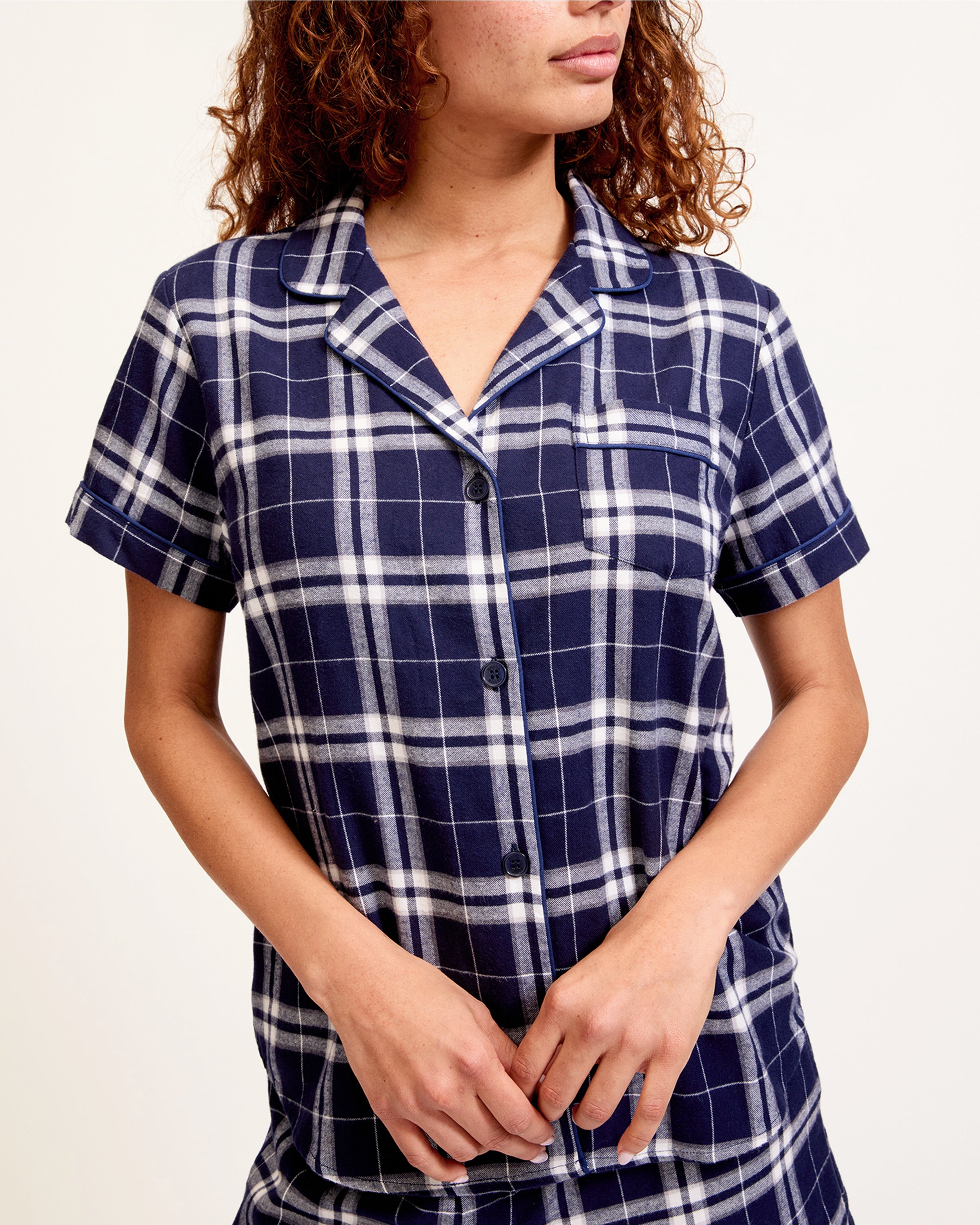 The Women's Brushed Twill Short Sleeve Short Set in Oxford Tartan features a navy and white plaid pattern, a short-sleeve button-up shirt with chest pocket, and drawstring shorts—perfect for a coordinated pajama look.
