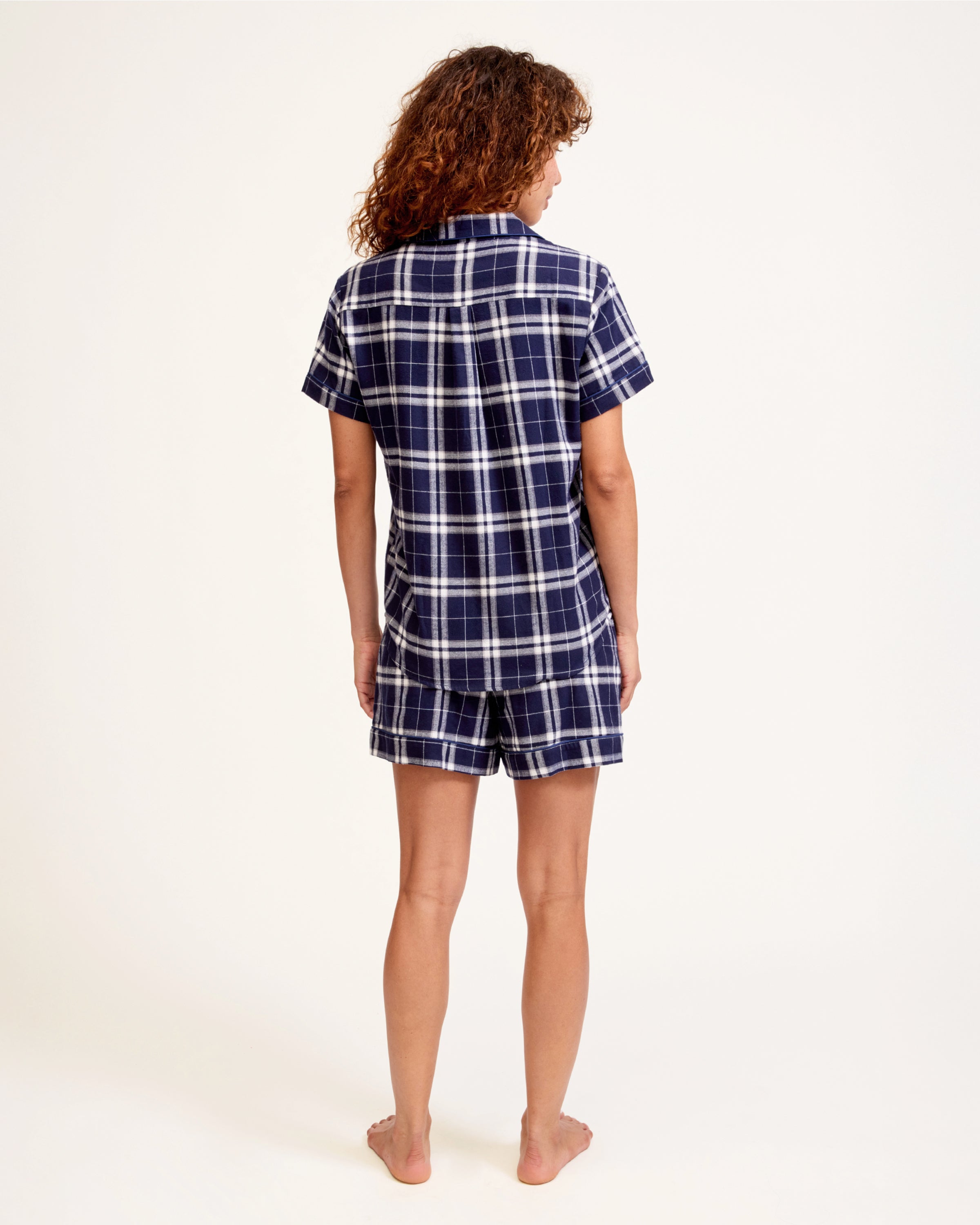 The Women's Brushed Twill Short Sleeve Short Set in Oxford Tartan features a navy and white plaid pattern, a short-sleeve button-up shirt with chest pocket, and drawstring shorts—perfect for a coordinated pajama look.