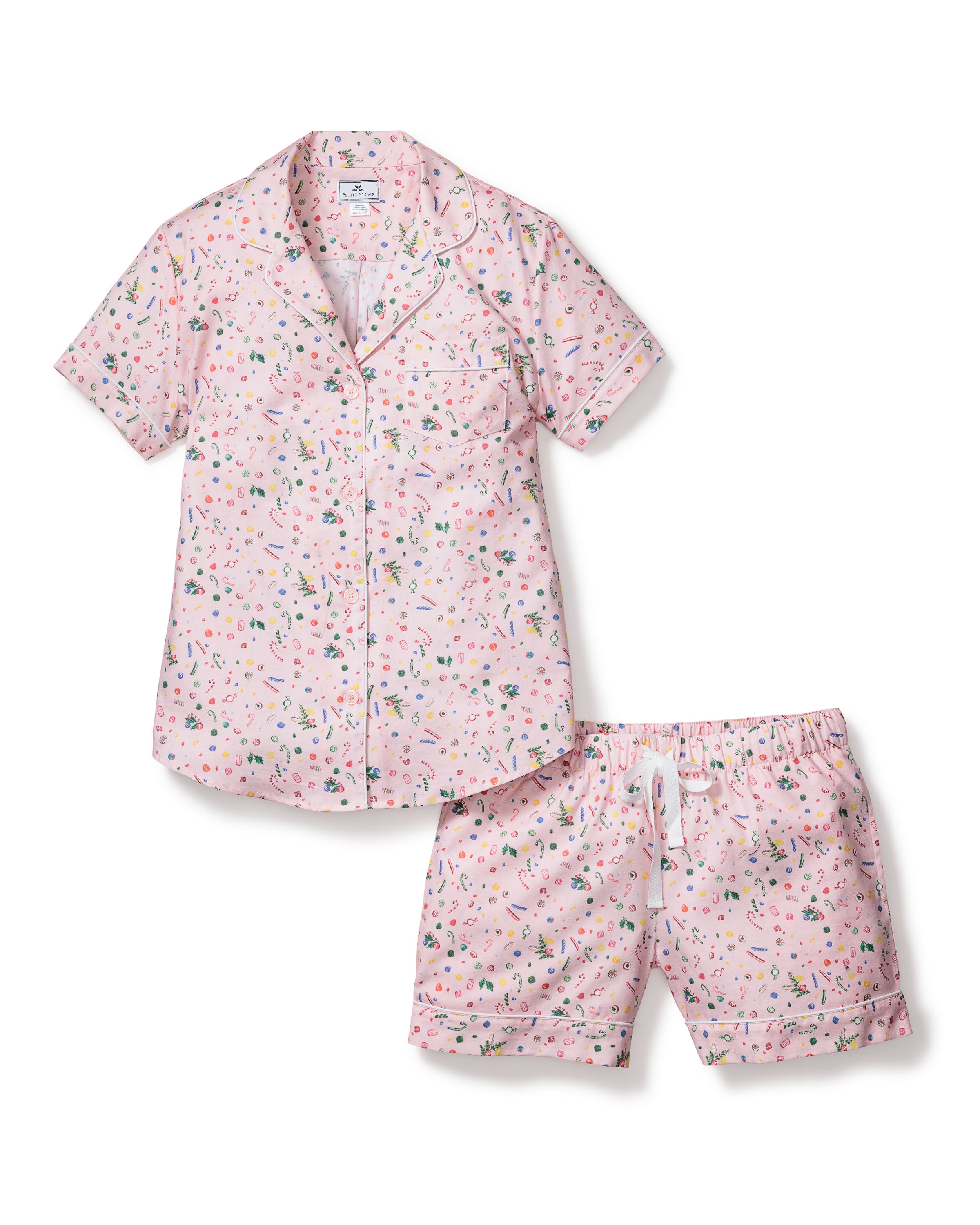 The Womens Twill Short Sleeve Short Set in Vintage Sweets by Petite Plume is 100% cotton, featuring a pink shirt with buttons and a pocket, plus shorts with an elastic waistband and drawstring, adorned with a colorful pattern of small shapes and objects for comfort.