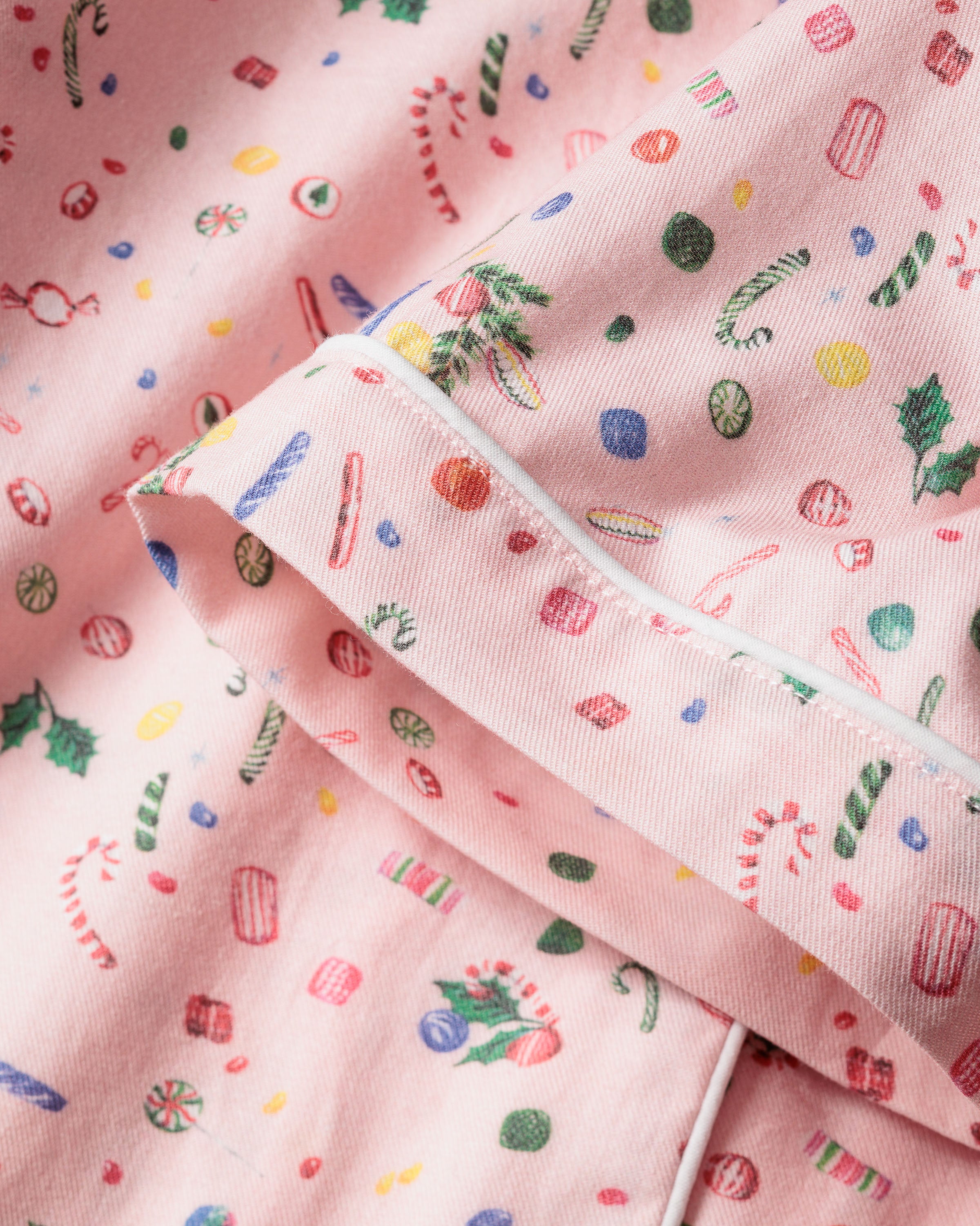 Close-up of Petite Plumes Womens Twill Short Sleeve Short Set in Vintage Sweets, featuring festive holiday sweets print on 100% cotton. The fabric showcases candy canes, holly leaves, and ornaments with white piping—ideal for a cozy pajama set.