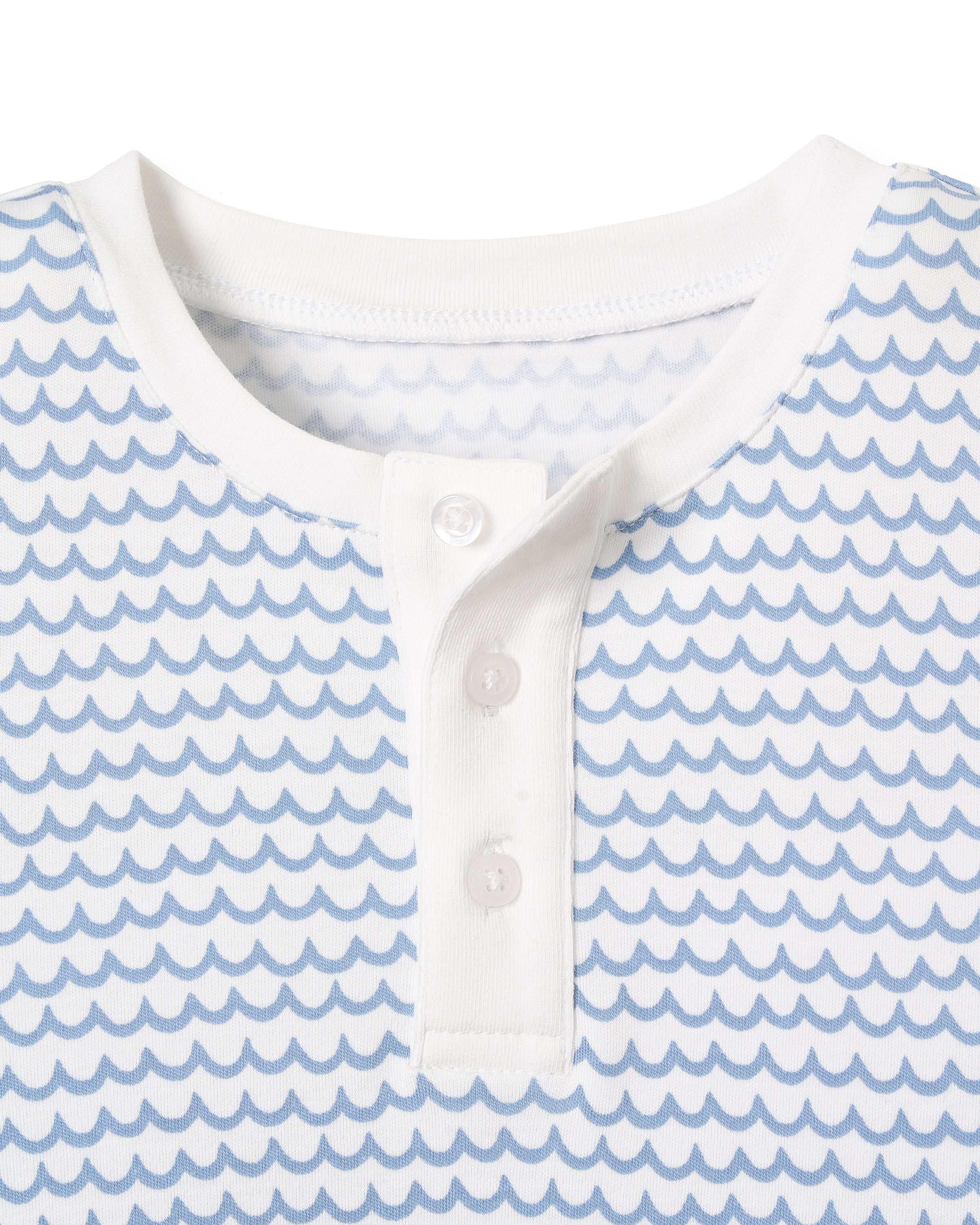 Close-up of the Kids Pima Snug Fit Pajama Set in La Mer by Petite Plume, featuring a white henley shirt with a light blue wave pattern, crafted from soft Pima Cotton. This long sleeve top has a round neckline and three white buttons on the placket, showcasing luxurious sleepwear style.