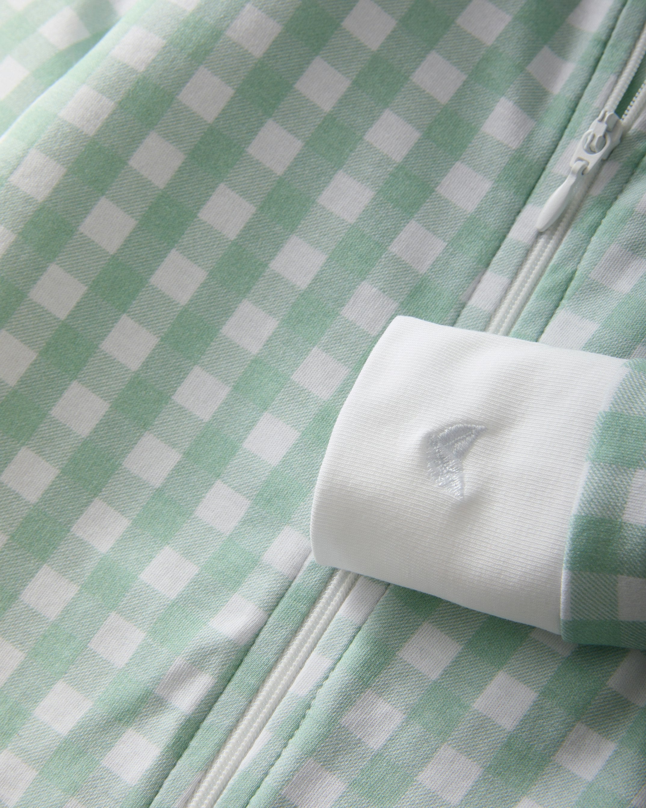 The Baby's Pima Romper PP x Bobbie features a mint green and white gingham pattern, long sleeves, white cuffs and collar, a diagonal neck-to-ankle zipper, and a small button at the neckline.