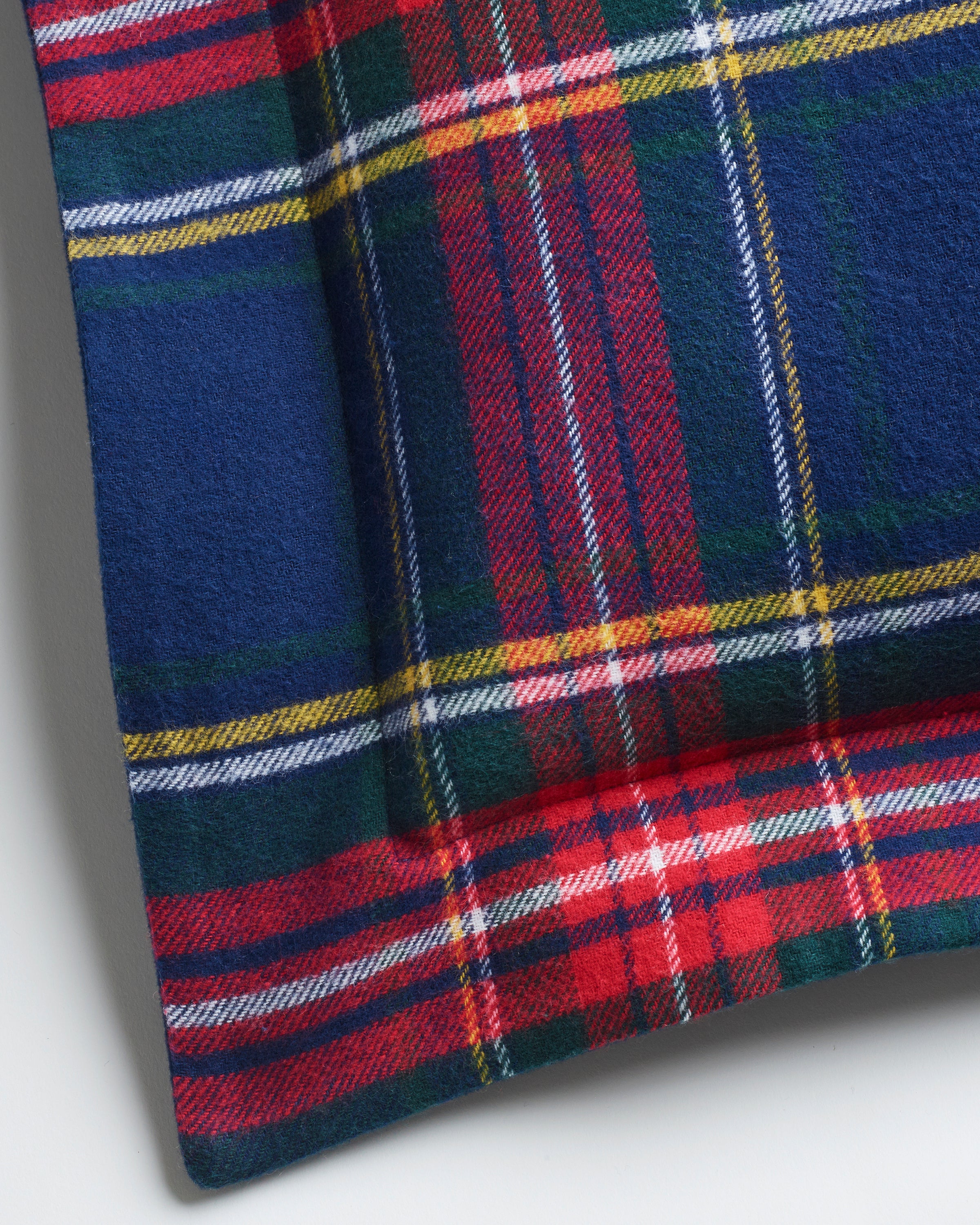 The Petite Plume Flannel Decorative Pillow in Windsor Tartan features a classic plaid design crafted from soft brushed cotton flannel with a pattern of red, blue, green, and yellow stripes forming squares and rectangles.