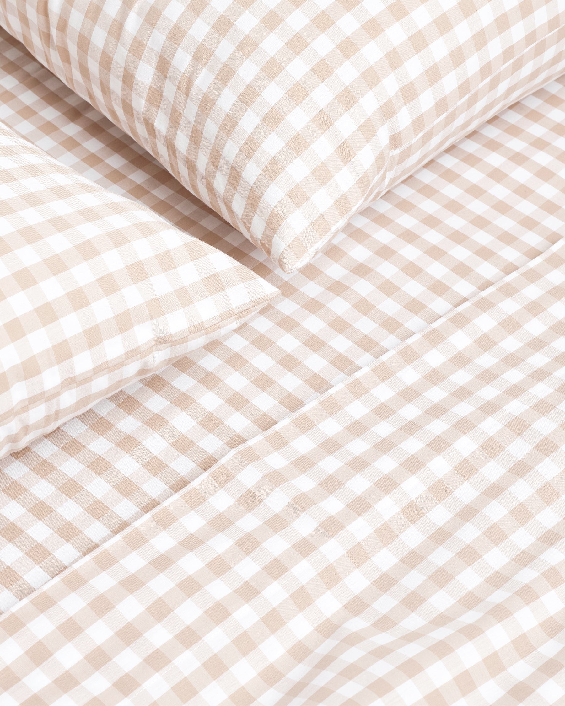 A neatly folded set of Luxe Premium Percale Bed Sheets in Camel Gingham, featuring a beige and white check pattern, displayed against a white background.