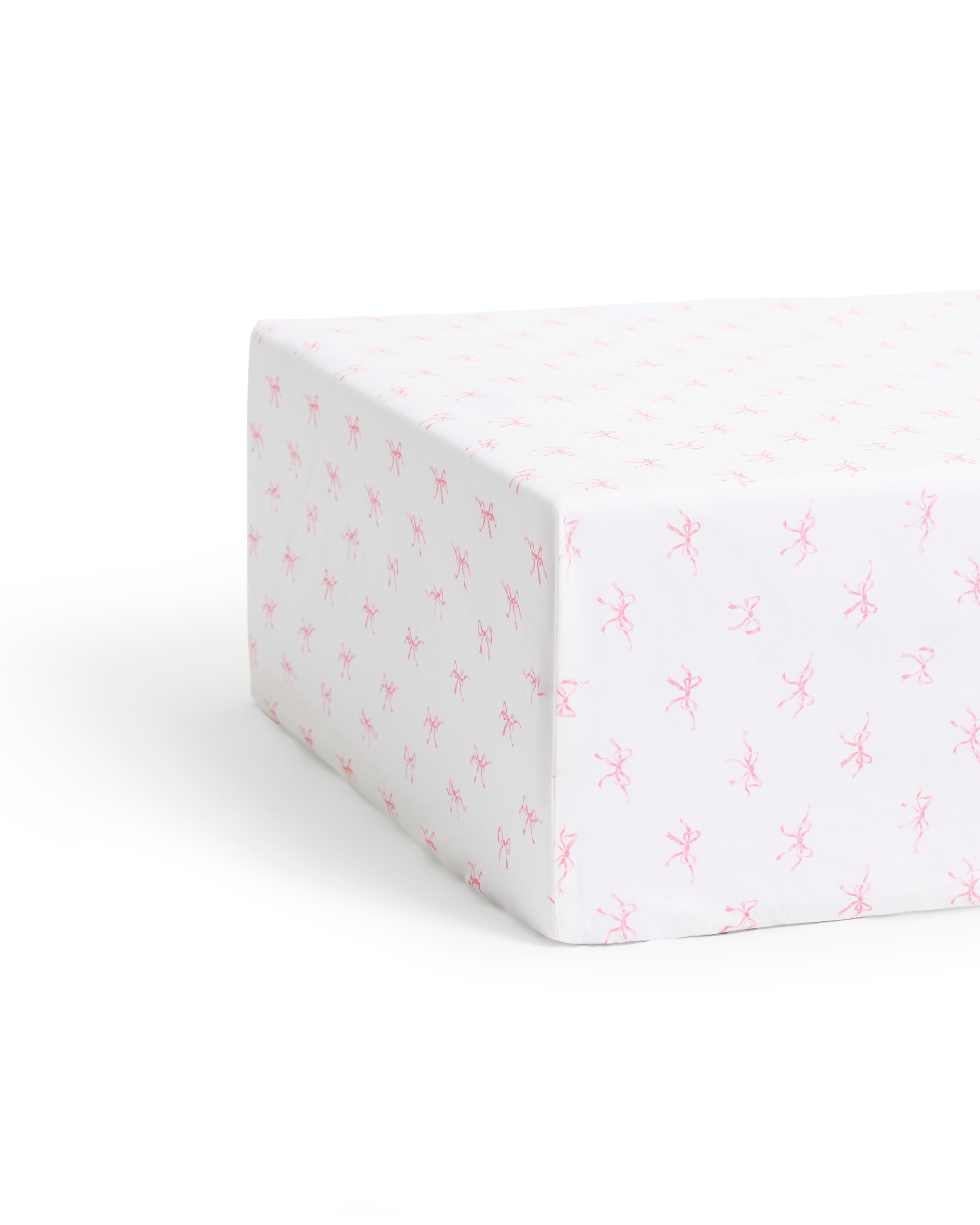 A close-up of the Luxe Premium Percale Crib Sheet in Blushing Bows, featuring a white background with a pattern of small pink ballerinas, neatly wrapped around the corner of a crib mattress.
