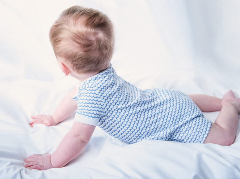 The back of a baby in a Light blue and white stripe pima romper