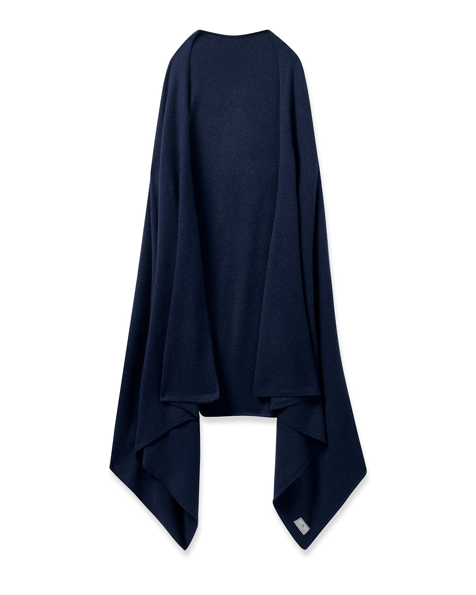 The Womens Cashmere Wrap in Navy by Petite Plume drapes elegantly with asymmetrical folds, exuding the softness of Grade A cashmere. Resembling a cozy shawl, it has a small label at the bottom right corner against a white backdrop, highlighting its luxurious appeal.