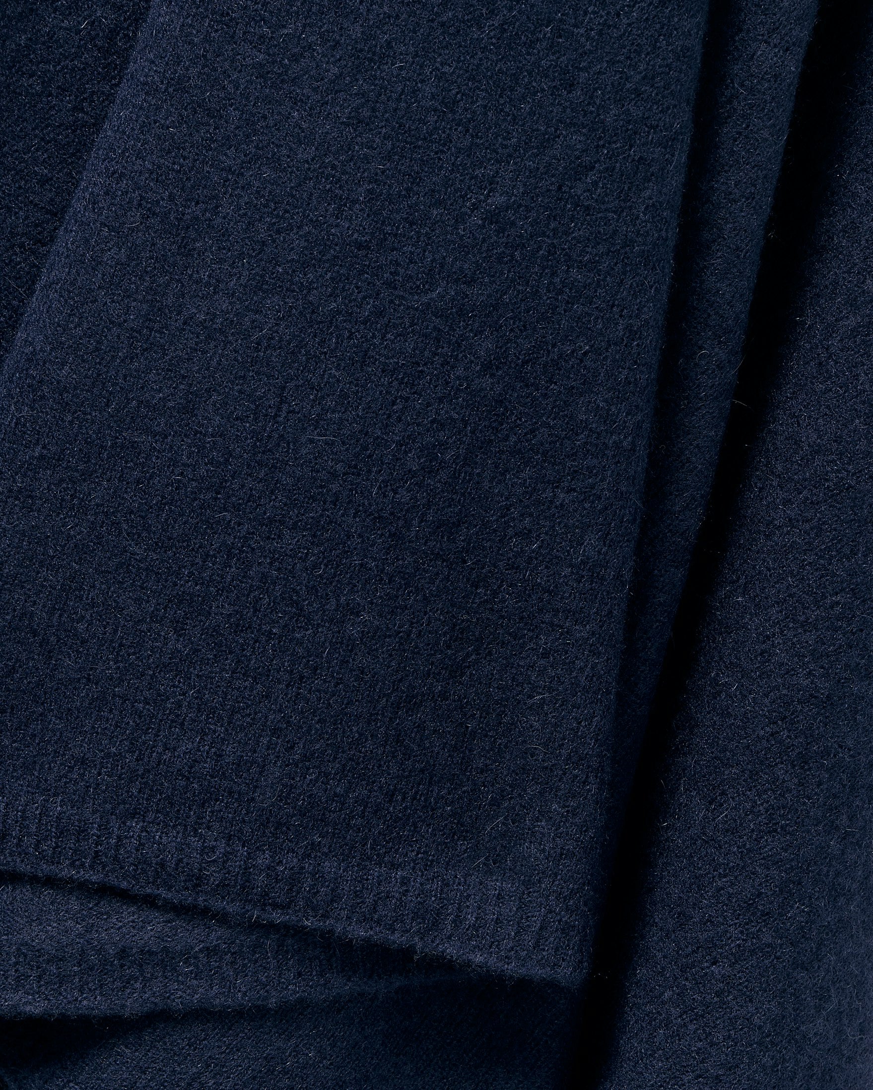Close-up of the Womens Cashmere Wrap in Navy by Petite Plume, showcasing soft, fuzzy Grade A cashmere. Overlapping folds evoke luxury scarf vibes, emphasizing thickness and warmth.