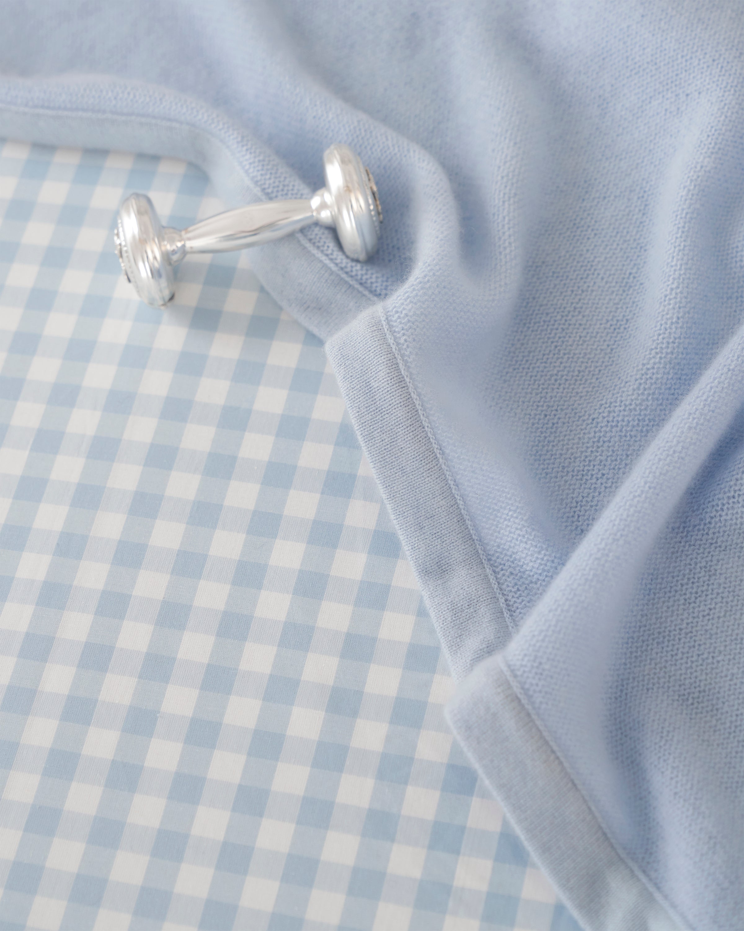 A neatly folded Cashmere Baby Blanket in Indigo by Petite Plume, with a luxuriously soft texture. The bottom right corner is slightly turned up, showcasing the underside. Edges are bordered with a darker indigo shade, evoking the elegance of a luxury baby gift.