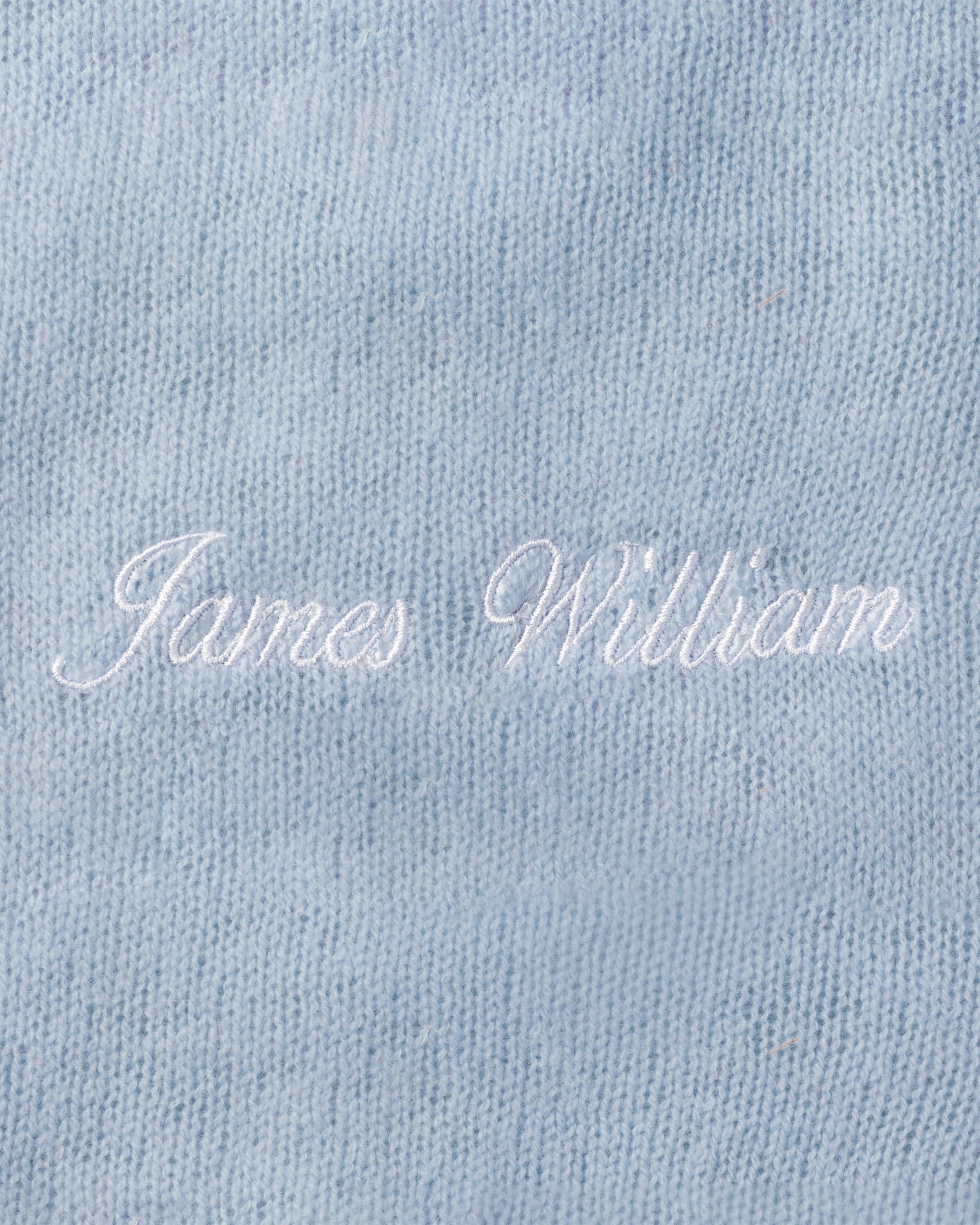 The image features a Petite Plume luxury baby gift: the Cashmere Baby Blanket in Indigo with James William embroidered in white cursive. Handmade in Nepal, it has a soft, slightly textured feel, perfect for welcoming little ones with style and comfort.