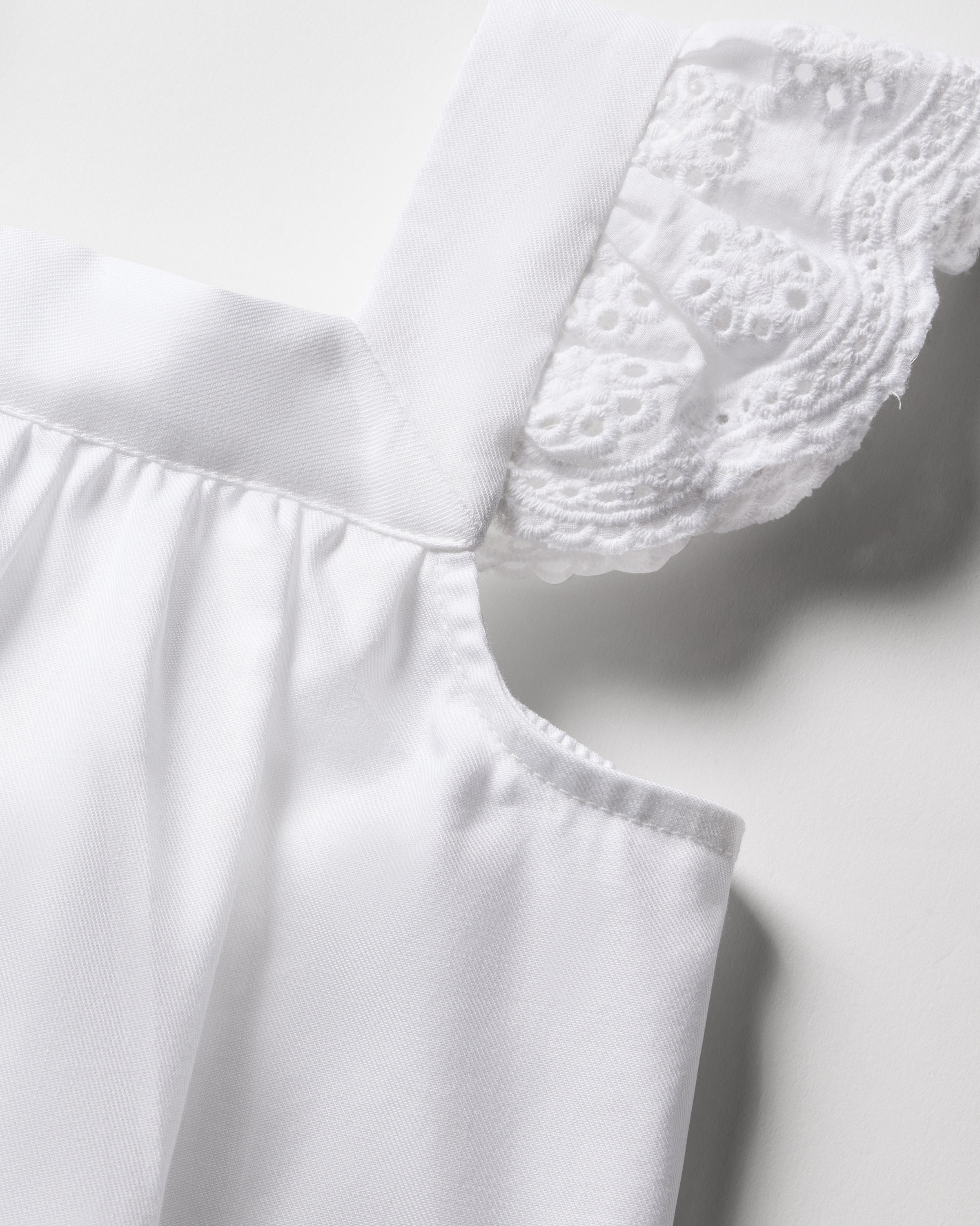 Close-up of Petite Plumes Girls Twill Clara Short Set in White, showcasing a lace detail on the shoulder. The intricate lace contrasts beautifully with the smooth, soft cotton texture, highlighting this exquisite sleepwears craftsmanship.