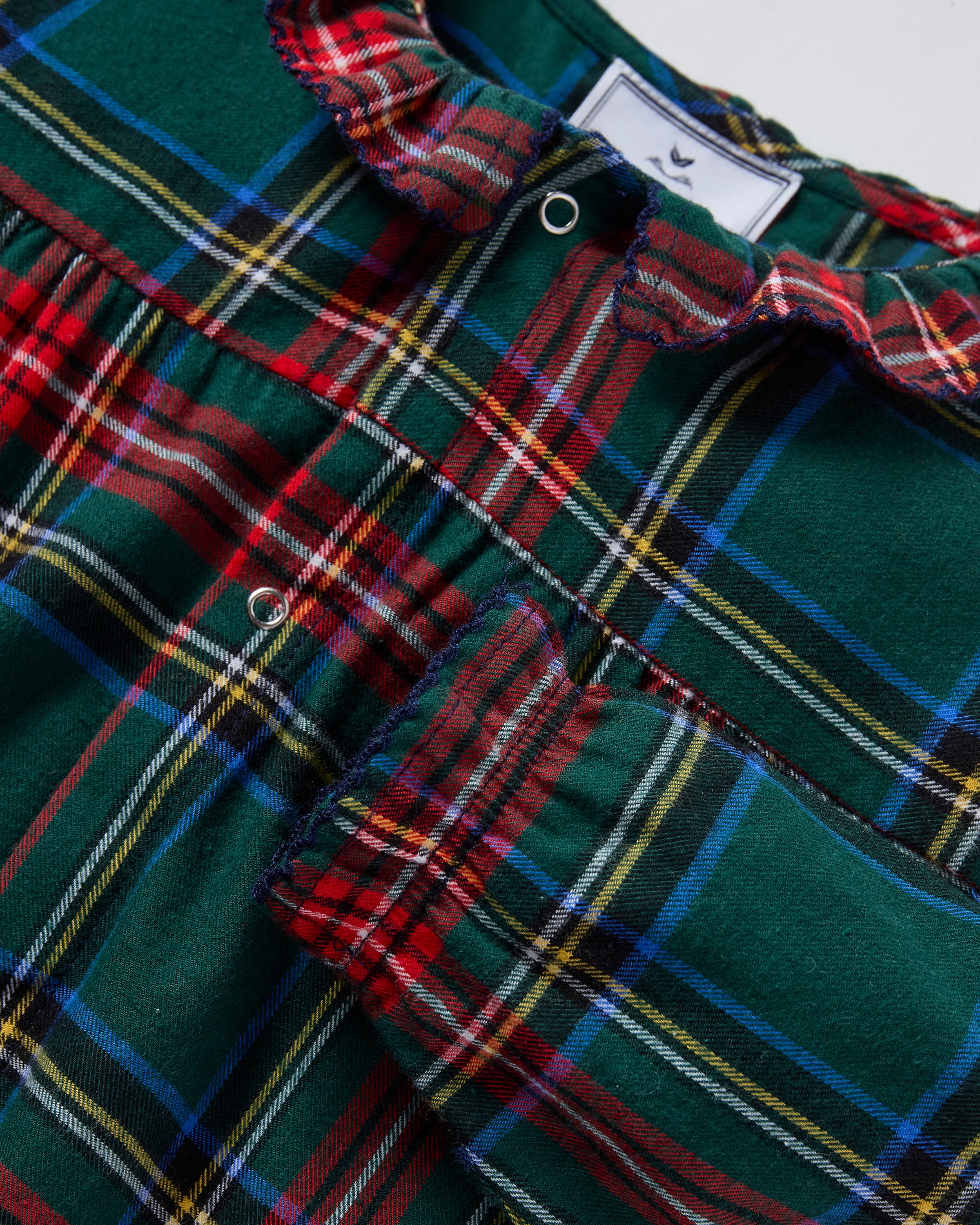 The Baby's Brushed Twill Madeline Romper in Kensington Tartan features a green, red, and yellow plaid print, ruffled collar, button front, and gathered cuffs at the wrists and ankles.