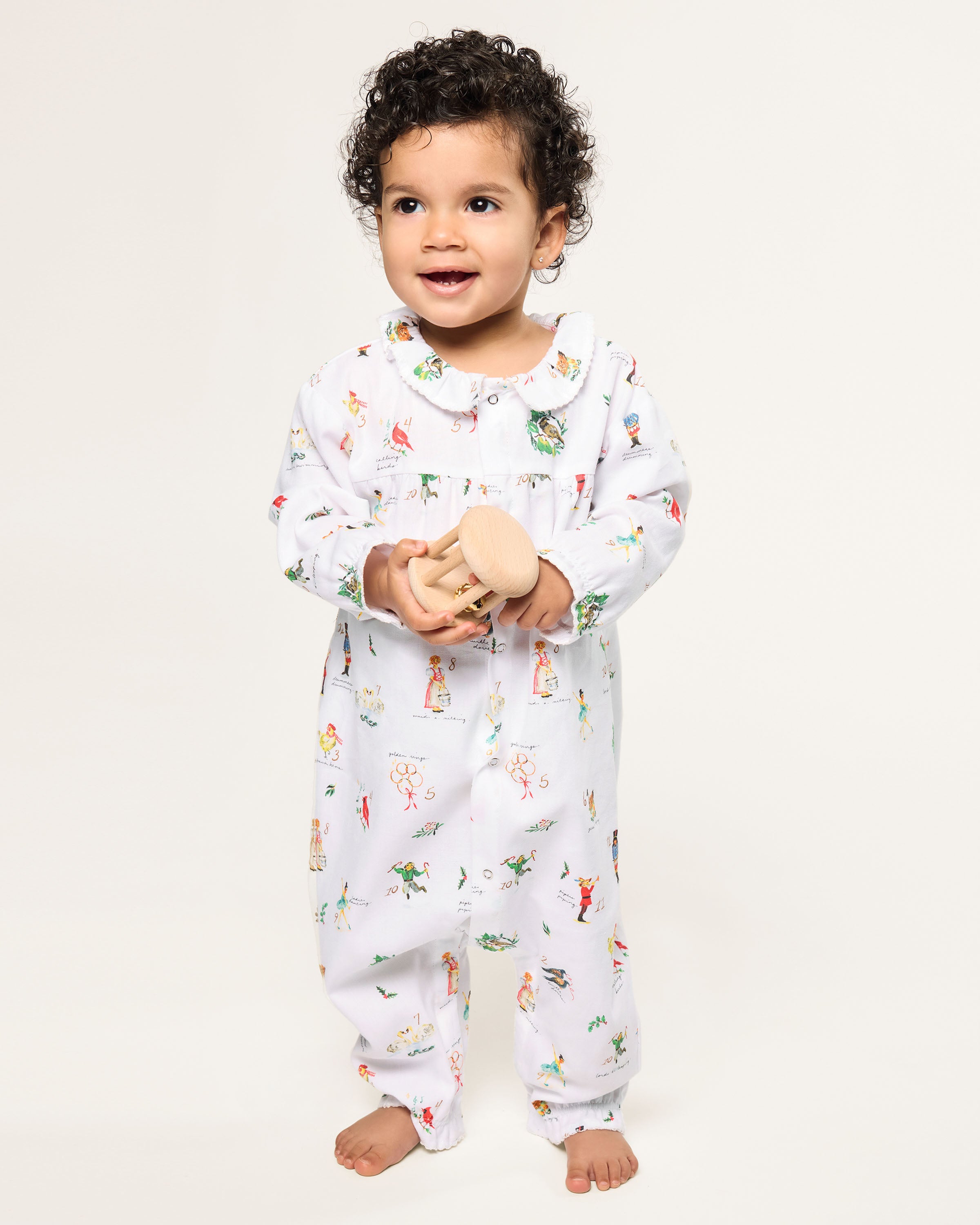 Baby's Twill Madeline Romper in 12 Days of Christmas: a white long-sleeve romper featuring colorful festive prints, a button-down front, and ruffled collar and cuffs.