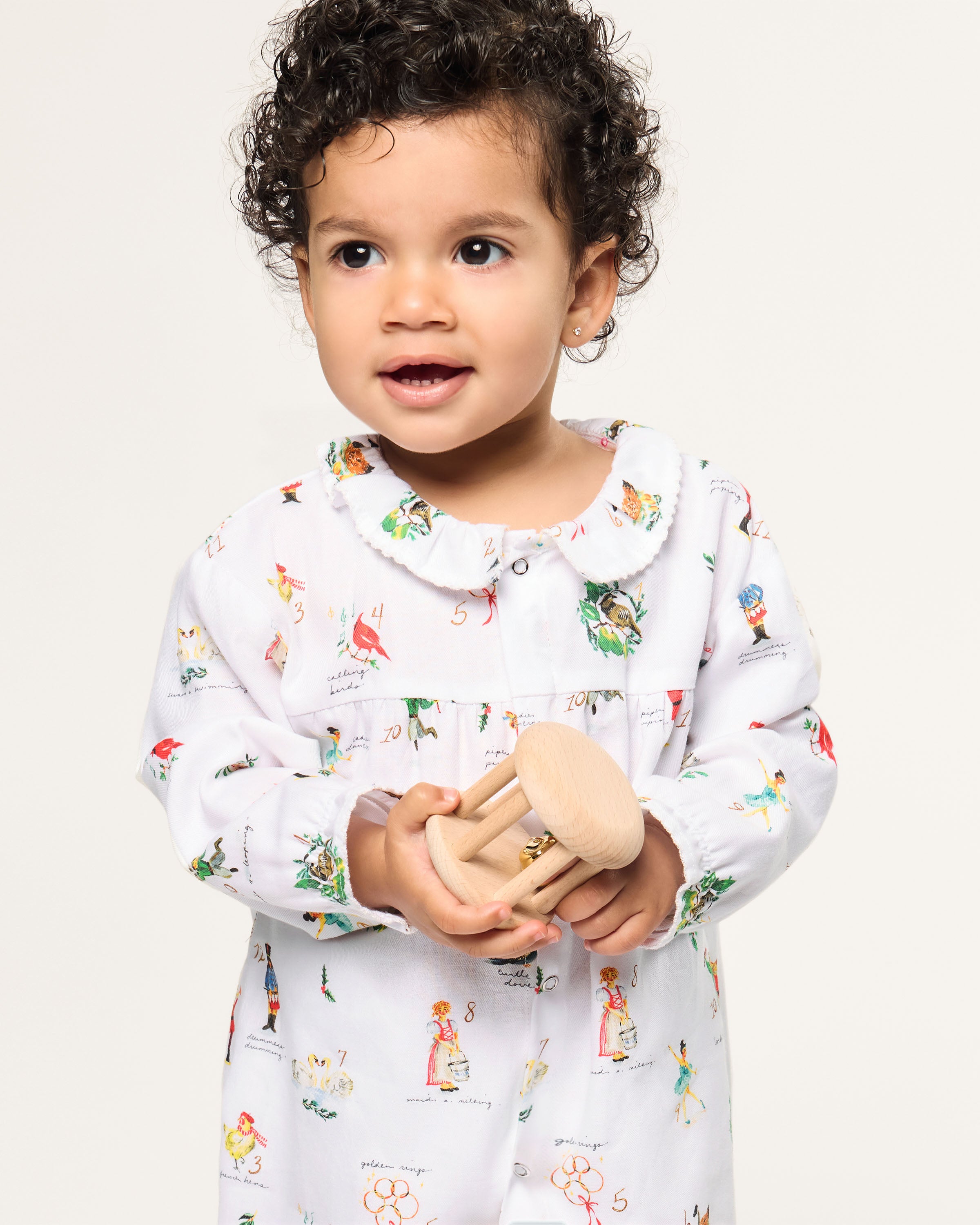 Baby's Twill Madeline Romper in 12 Days of Christmas: a white long-sleeve romper featuring colorful festive prints, a button-down front, and ruffled collar and cuffs.