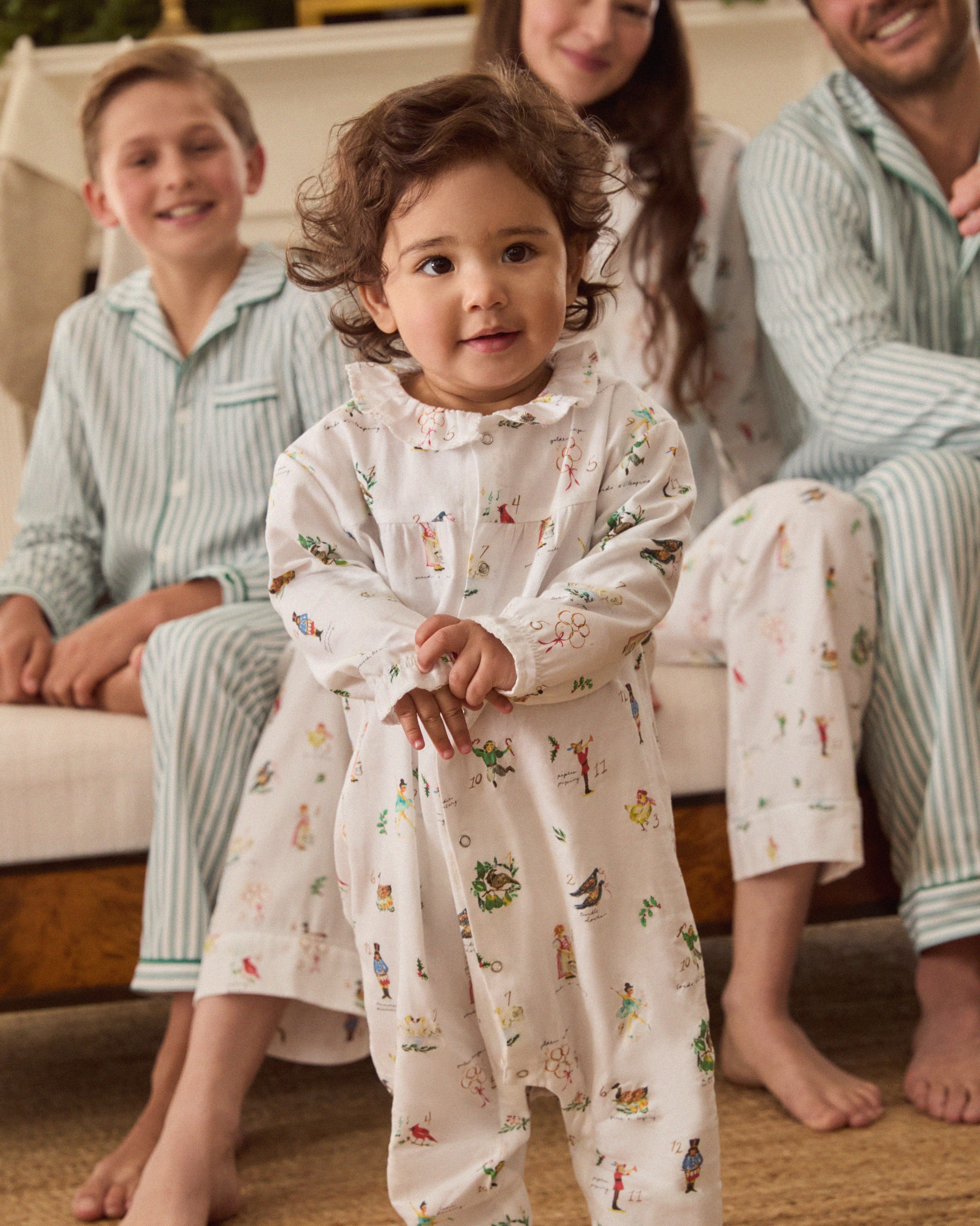 Baby's Twill Madeline Romper in 12 Days of Christmas: a white long-sleeve romper featuring colorful festive prints, a button-down front, and ruffled collar and cuffs.