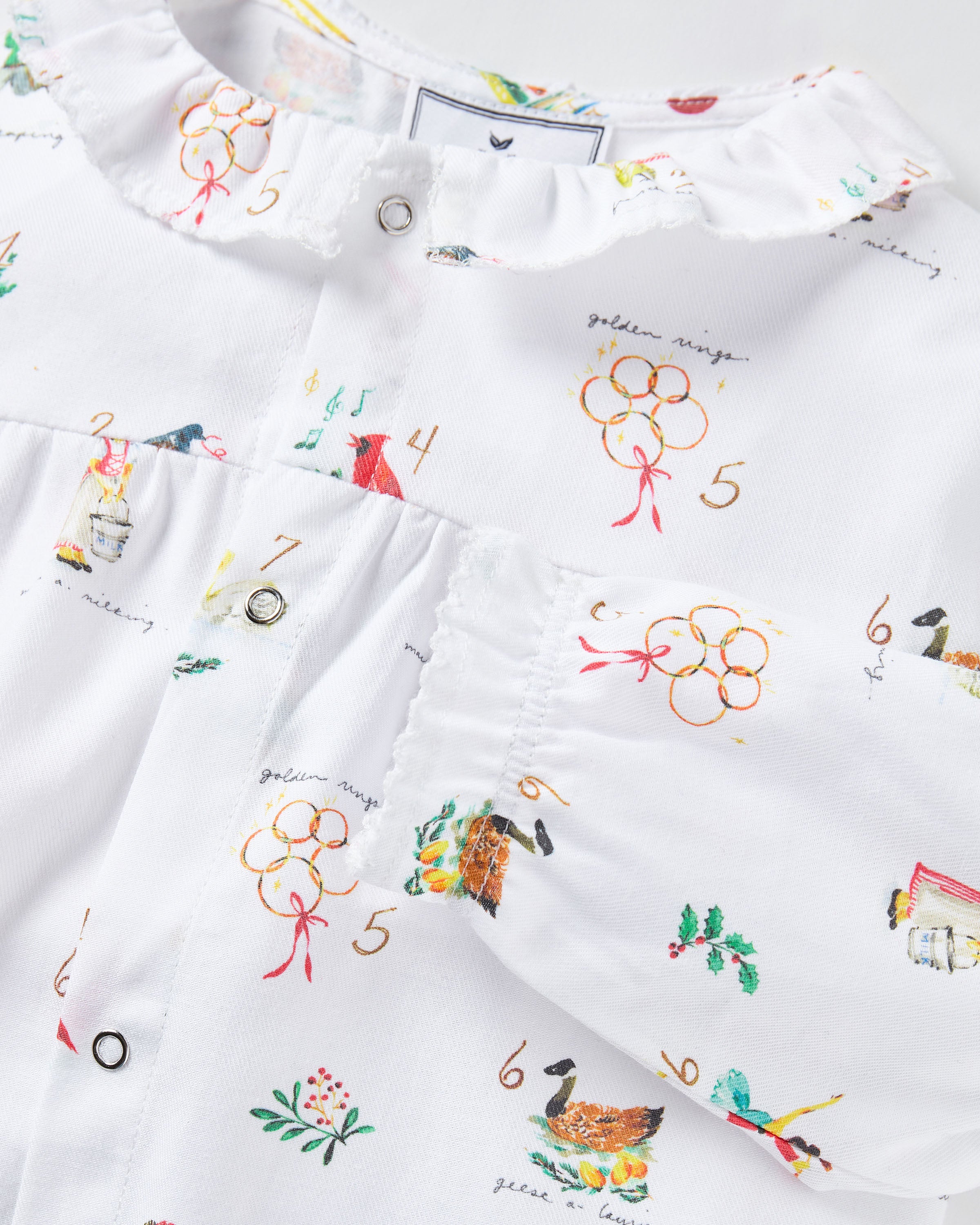 Baby's Twill Madeline Romper in 12 Days of Christmas: a white long-sleeve romper featuring colorful festive prints, a button-down front, and ruffled collar and cuffs.