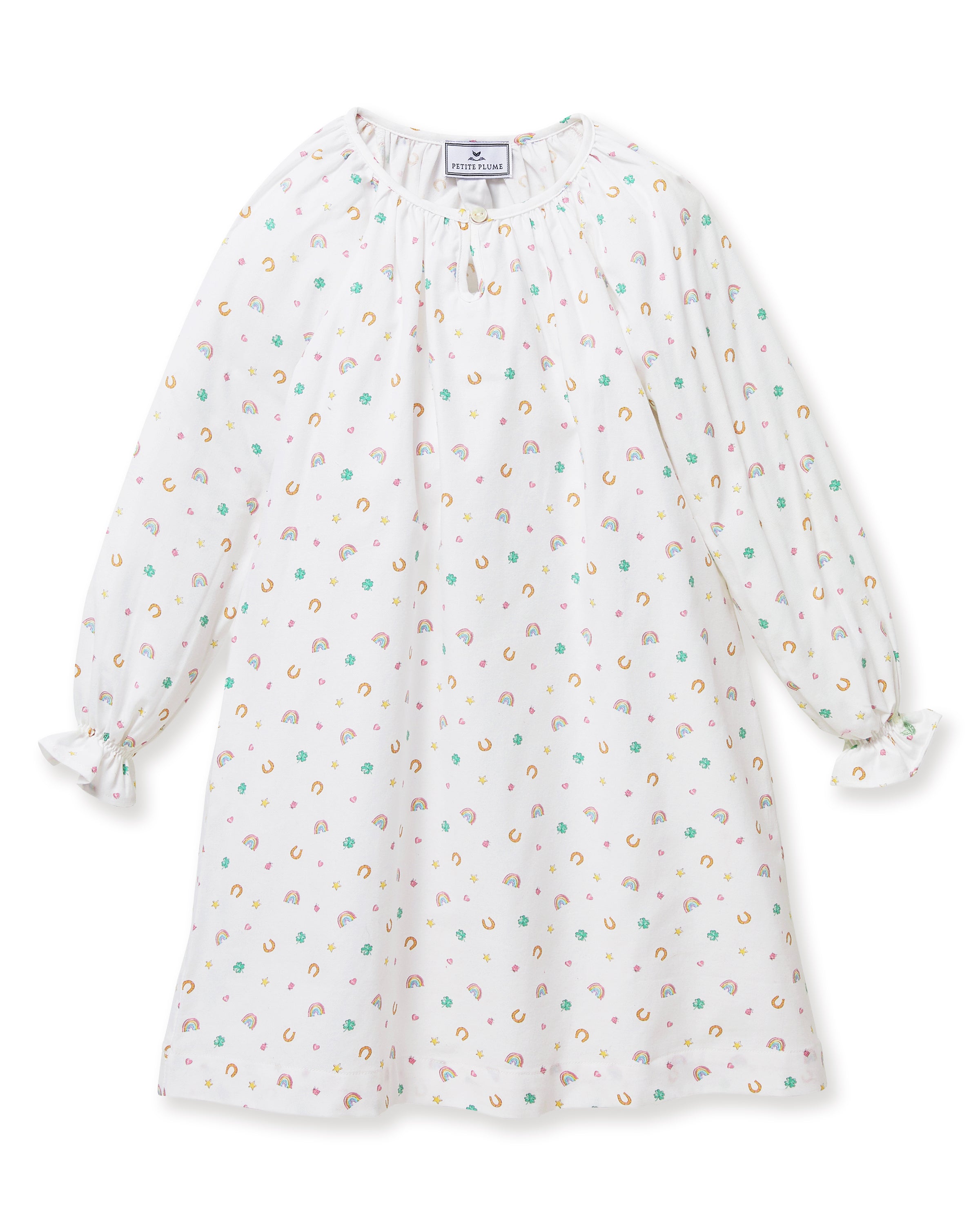 A young girl stands barefoot on a light background, wearing the Girl's Twill Delphine Nightgown in Good Luck Charms. She gazes upward thoughtfully, showcasing its long sleeves and colorful pattern.
