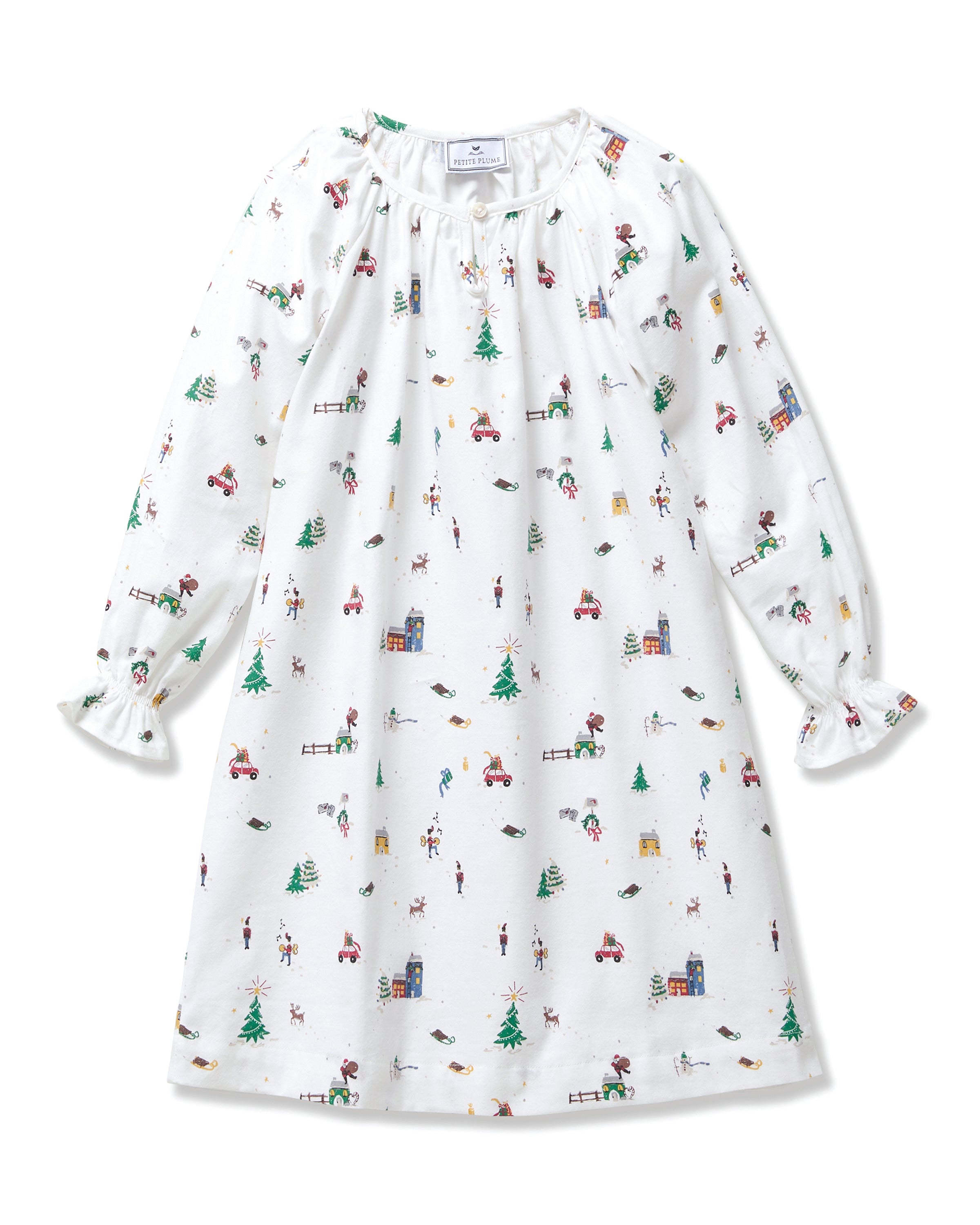The Girl's Twill Delphine Nightgown in Holiday Town is a white, long-sleeved children's nightgown with colorful festive prints and features ruffled cuffs and a gathered neckline.