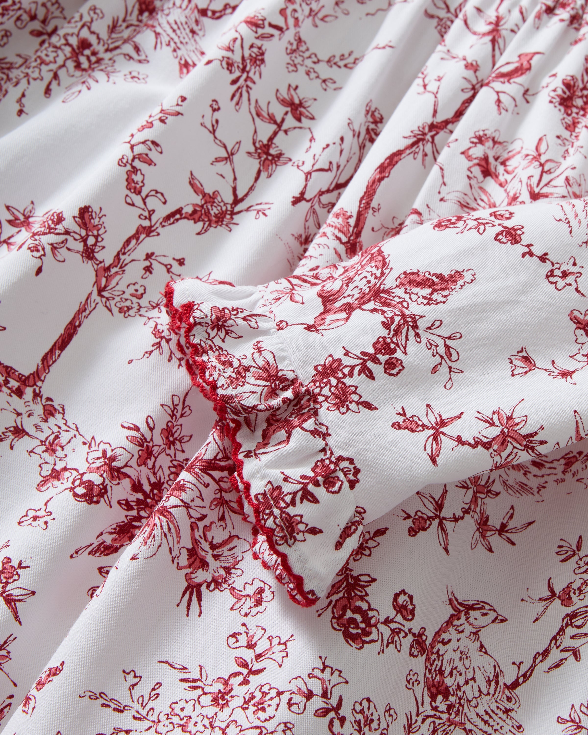 The Girl's Twill Eloise Nightgown in Red Timeless Toile features long sleeves, a white base with red nature-inspired print, gathered yoke, ruffled cuffs, and a scalloped Peter Pan collar.