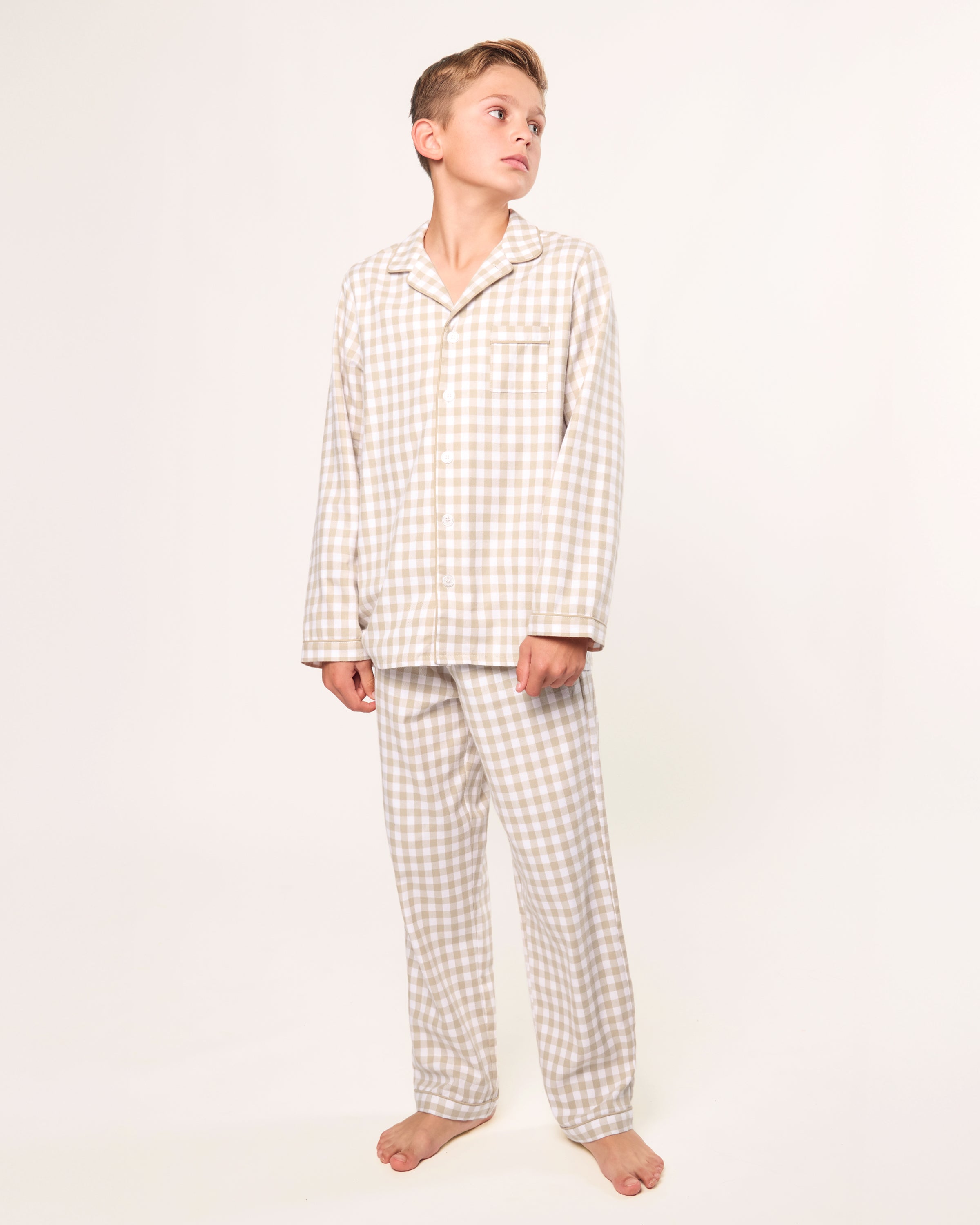 Kid's Twill Pajama Set in Camel Gingham features long sleeves, pants with an elastic waistband, and a button-up shirt with a collar and front pocket, all in a beige and white gingham check pattern.