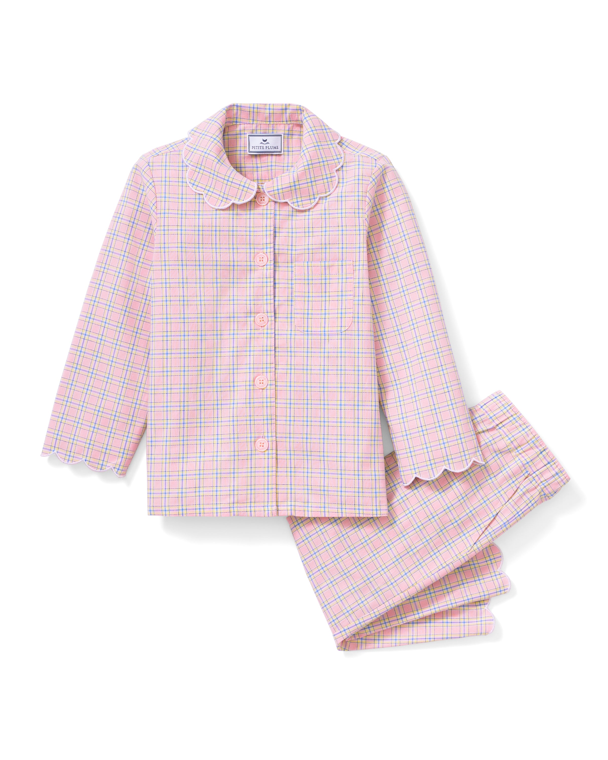 Young girl with long blonde hair wears the Kid's Twill Colette Pajama Set in Peony Plaid, featuring pink and white checks, scalloped edges, and stands barefoot against a plain light background.