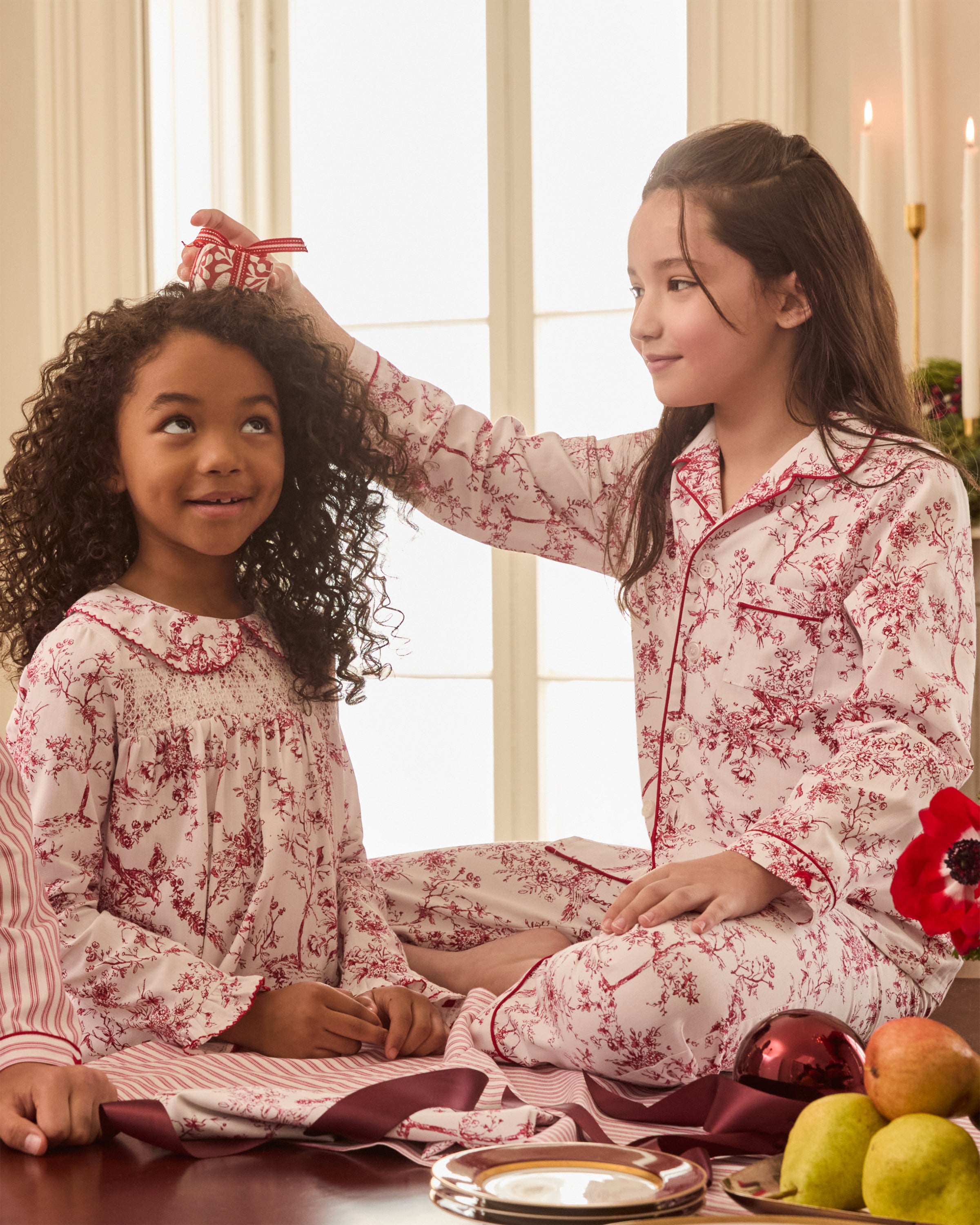 The Kid's Twill Pajama Set in Red Timeless Toile features a white base with red toile print, long-sleeve button-up top with front pocket, matching pants, and red piping accents.