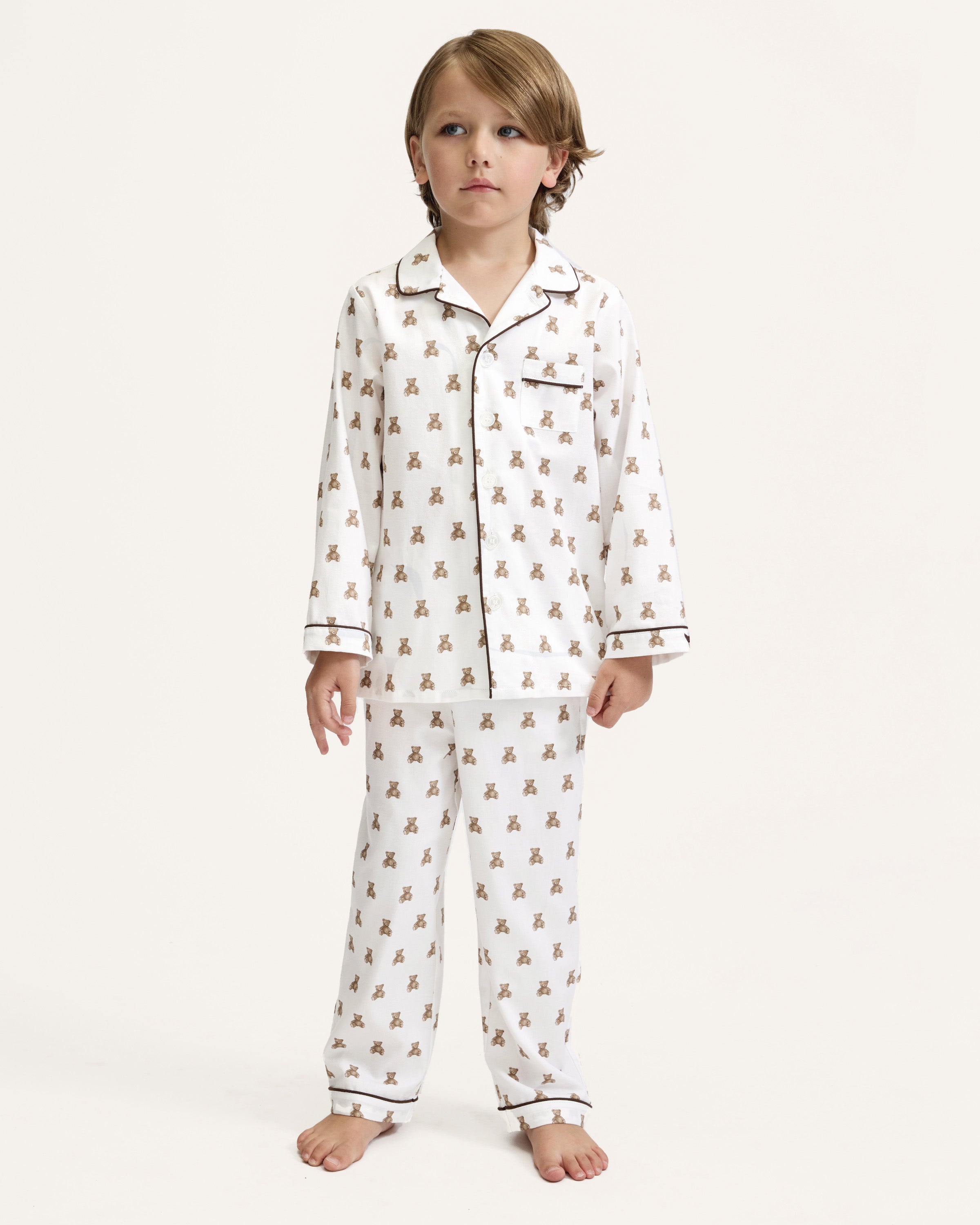 Kid's Twill Pajama Set in Teddy Tales: white long-sleeve, button-up pajamas with pants, featuring brown teddy bear print, dark piping along edges and chest pocket.