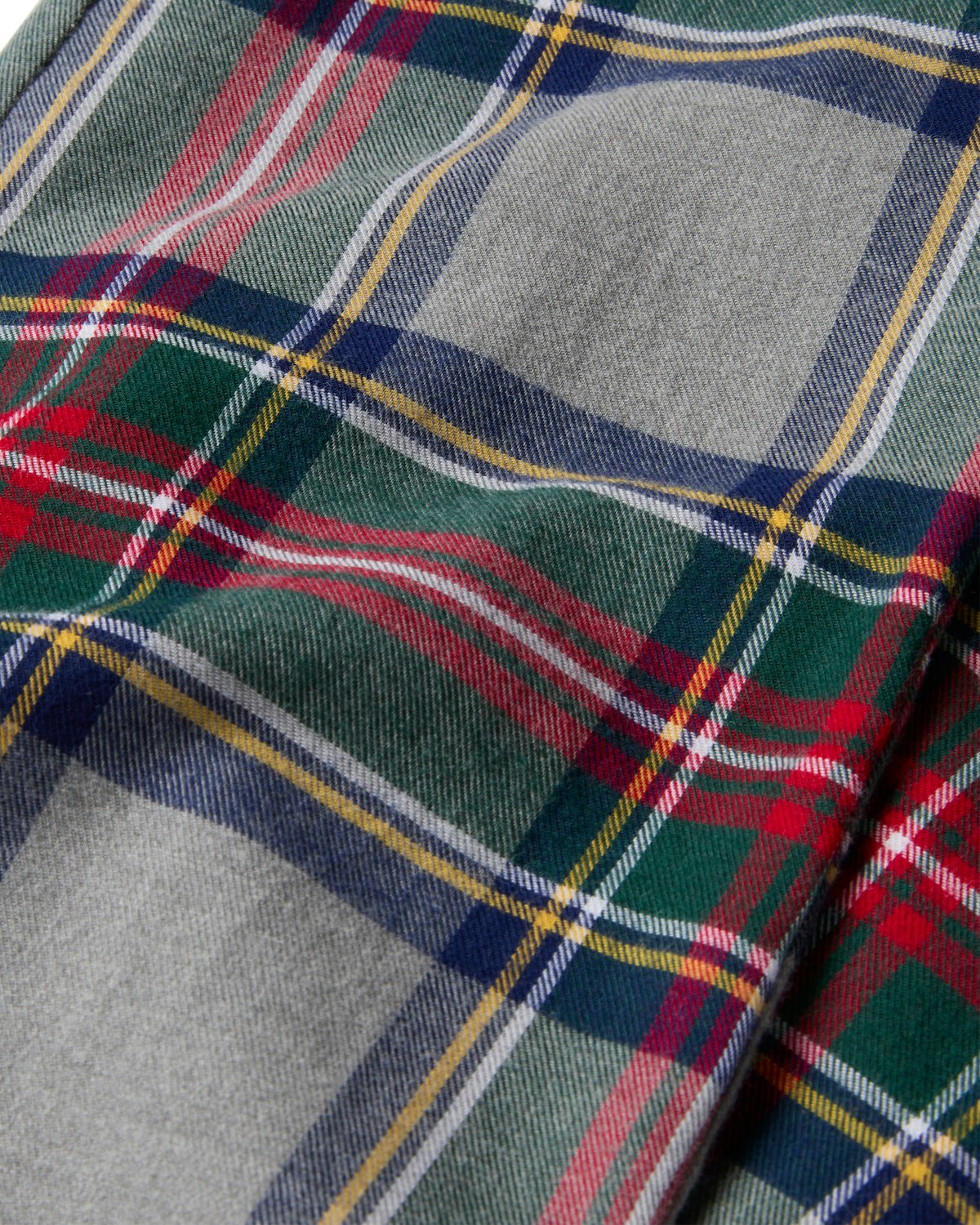The Kids Brushed Cotton Pajama Pant in Westminster Tartan by Petite Plume features a vibrant plaid pattern with red, green, blue, yellow, and white stripes on gray. Its textured weave is perfect for stylish yet flame-retardant fabric applications.