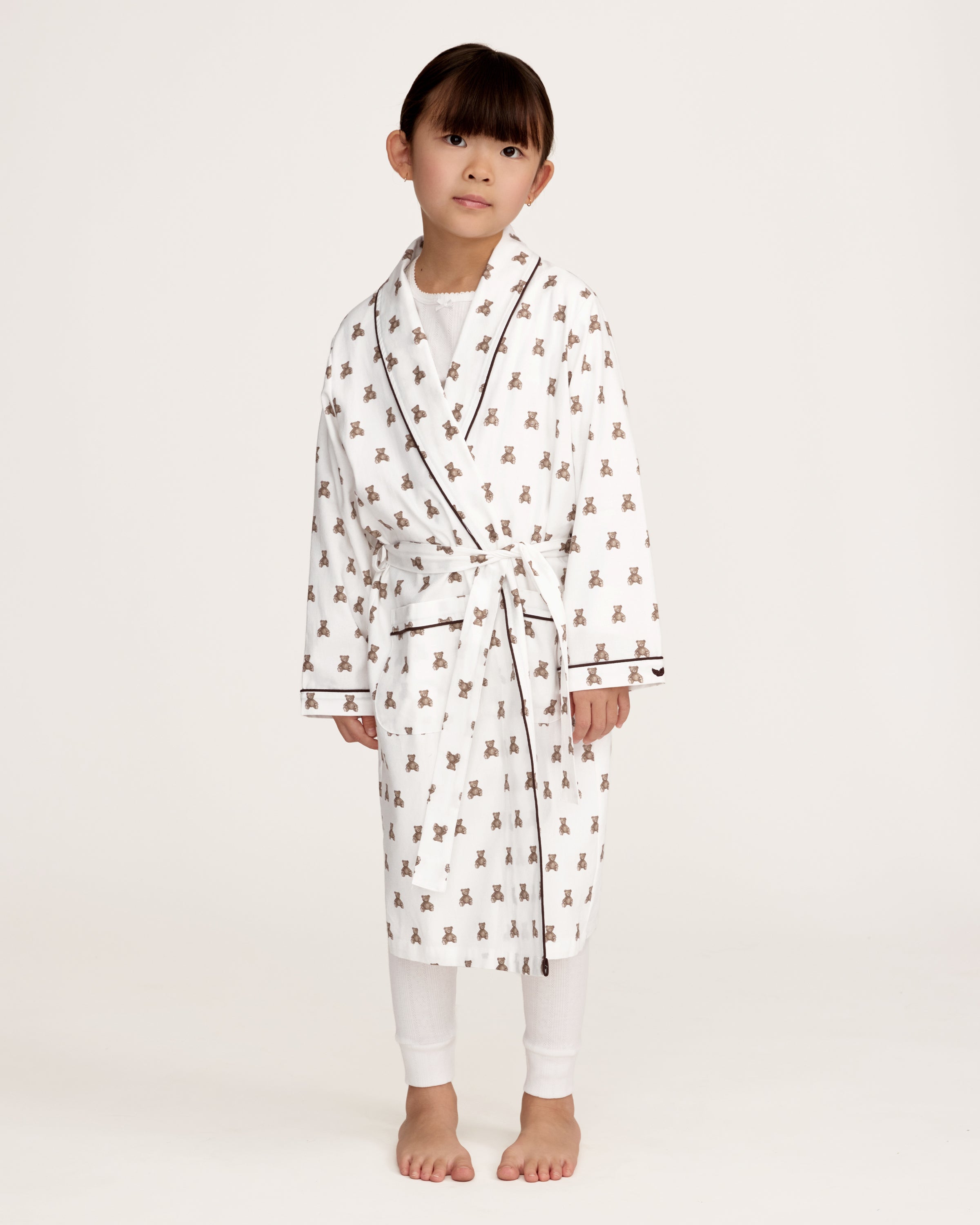 The Kid's Brushed Twill Robe in Teddy Tales features a white base with brown bear prints, black piping, two front pockets, and a matching waist belt.