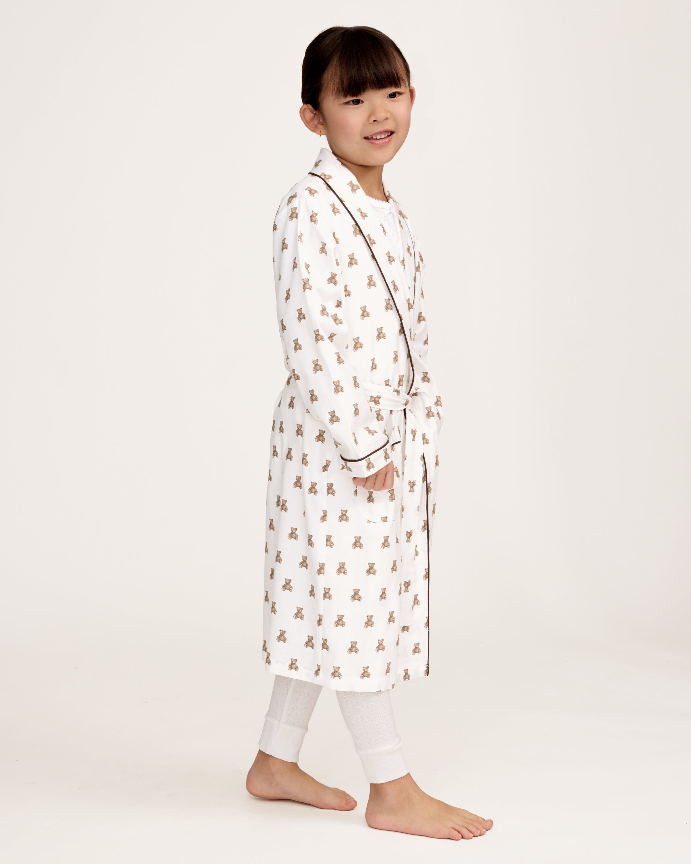 The Kid's Brushed Twill Robe in Teddy Tales features a white base with brown bear prints, black piping, two front pockets, and a matching waist belt.