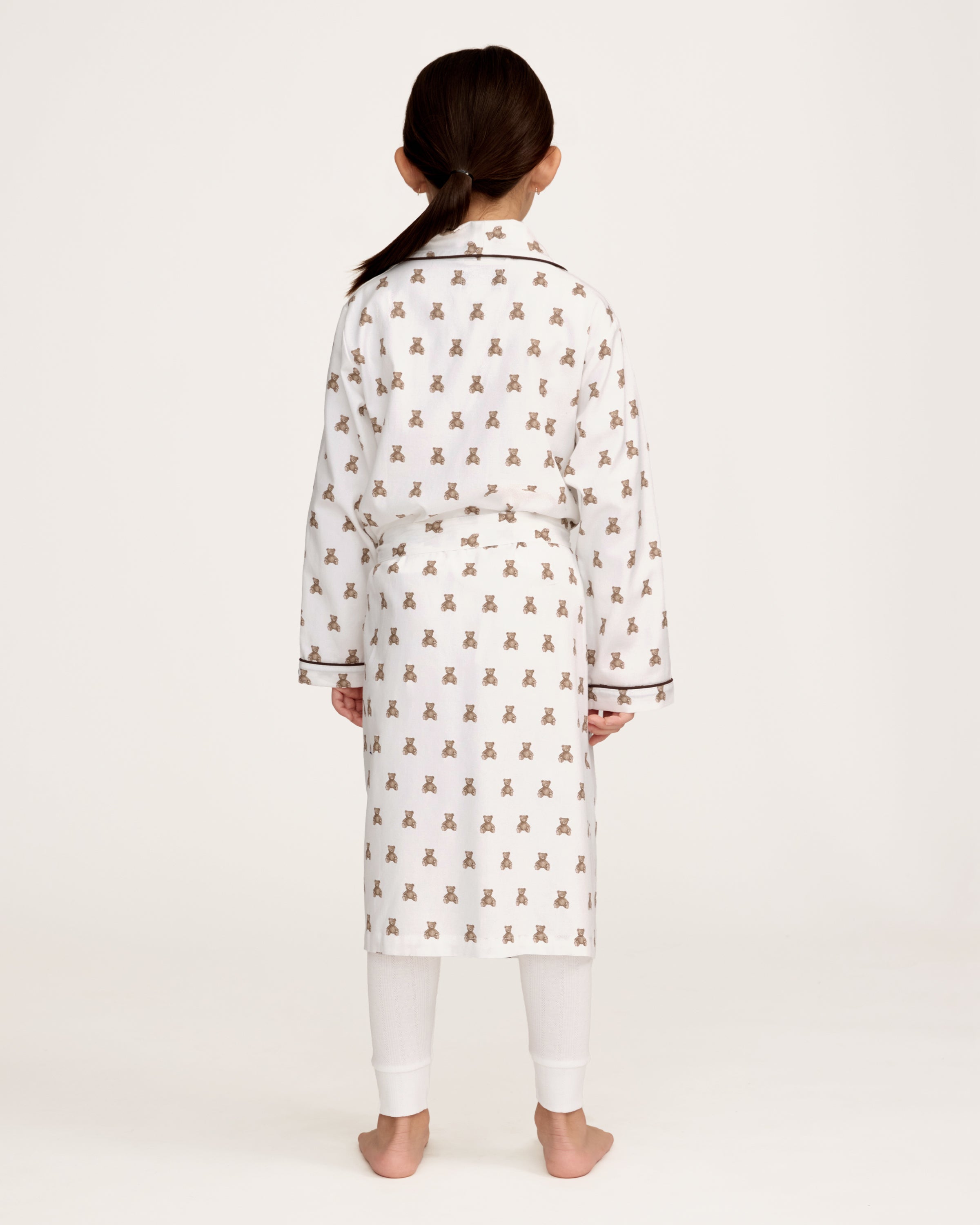 The Kid's Brushed Twill Robe in Teddy Tales features a white base with brown bear prints, black piping, two front pockets, and a matching waist belt.