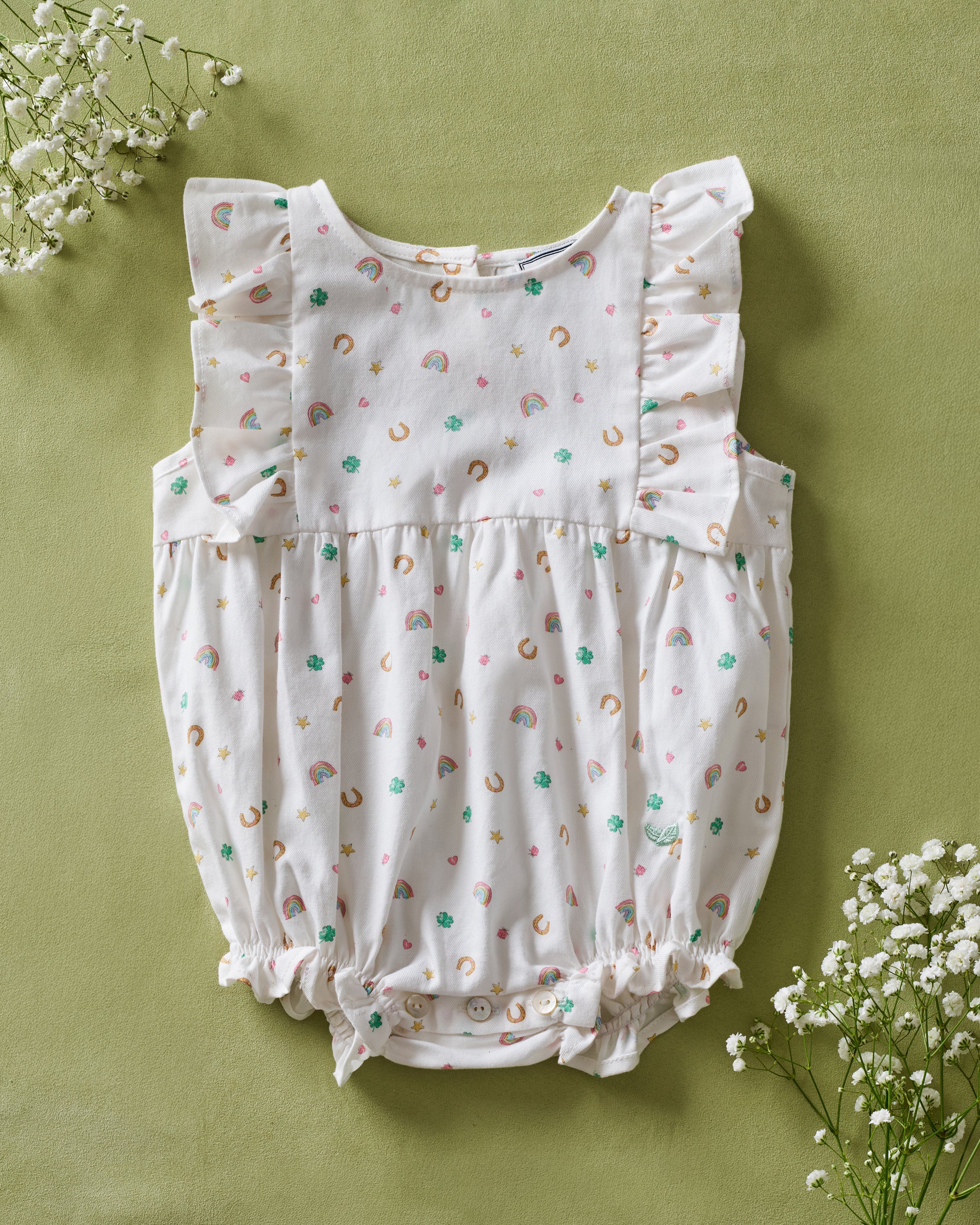 Baby's Twill Ruffled Romper in Good Luck Charms features small colorful prints of rainbows, horseshoes, clovers, and stars, ruffled sleeves, elastic leg openings, and a tag at the neckline.