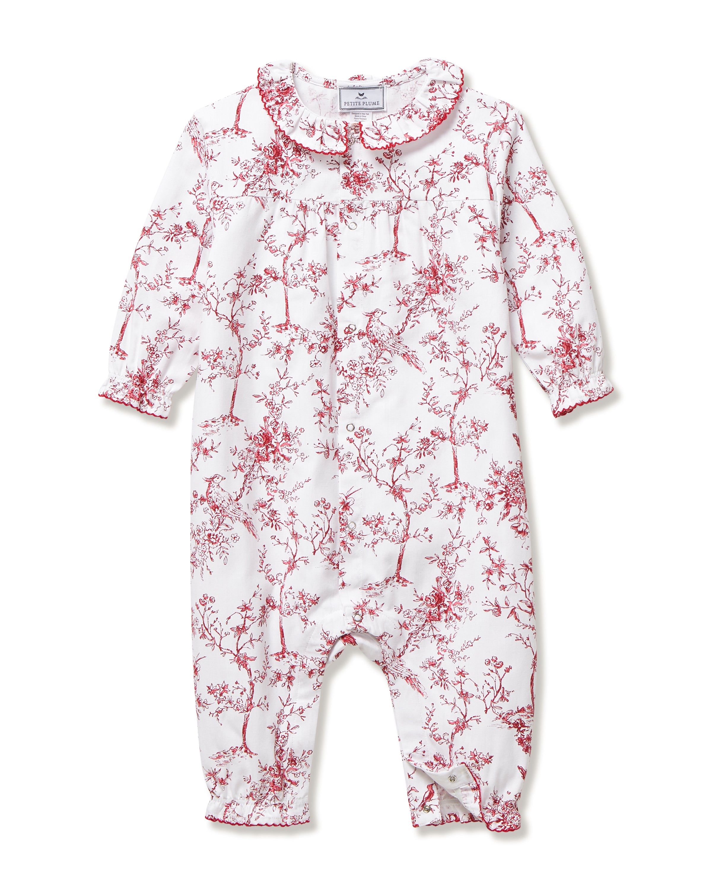 The Baby's Twill Madeline Romper in Red Timeless Toile features long sleeves, a ruffled collar, red floral print, and snap buttons down the front and legs.
