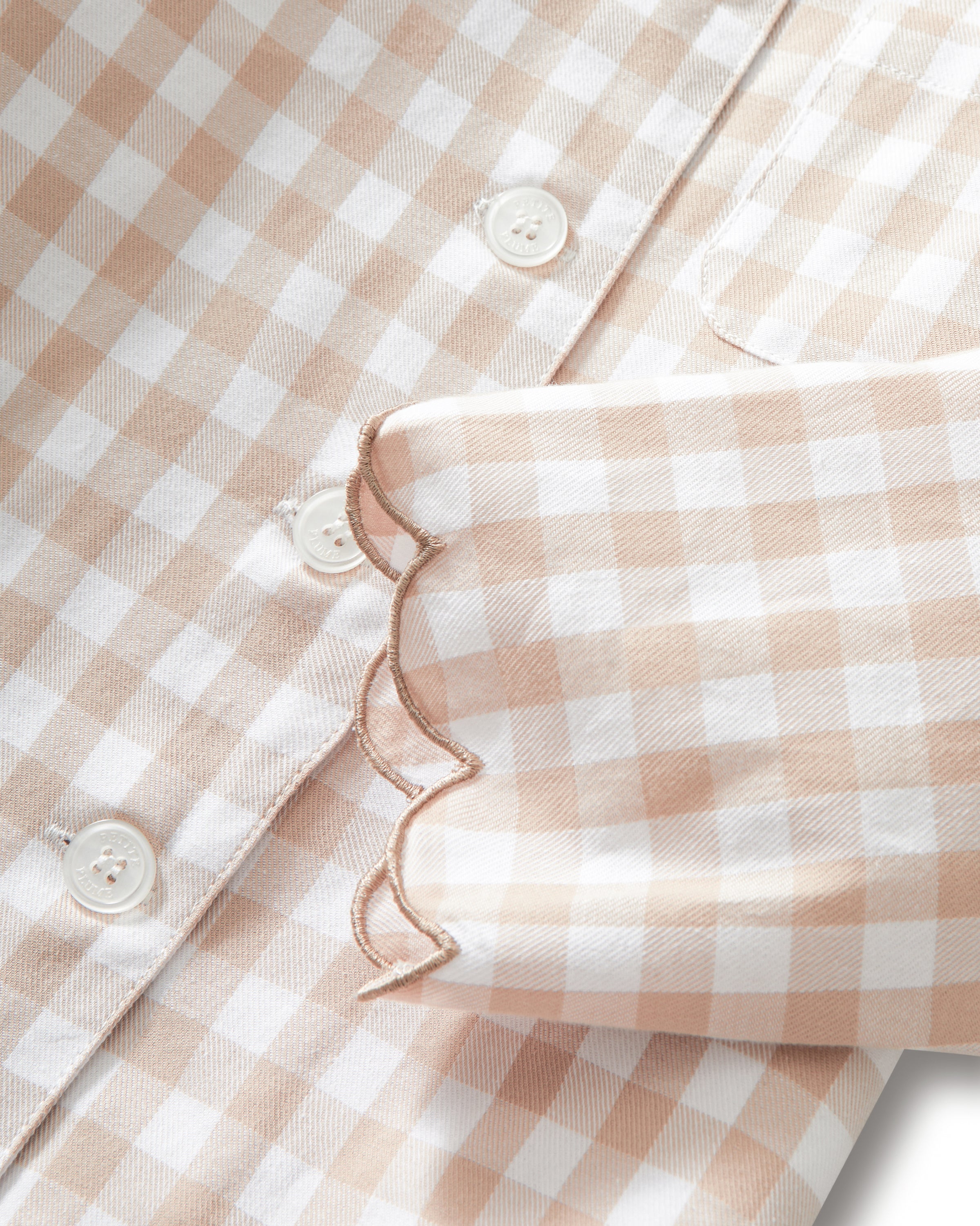 Kid's Twill Colette Pajama Set in Camel Gingham, featuring a beige and white gingham pattern with a scalloped collar, long sleeves, front pocket, and matching elastic-waist pants, is displayed neatly on a white background.