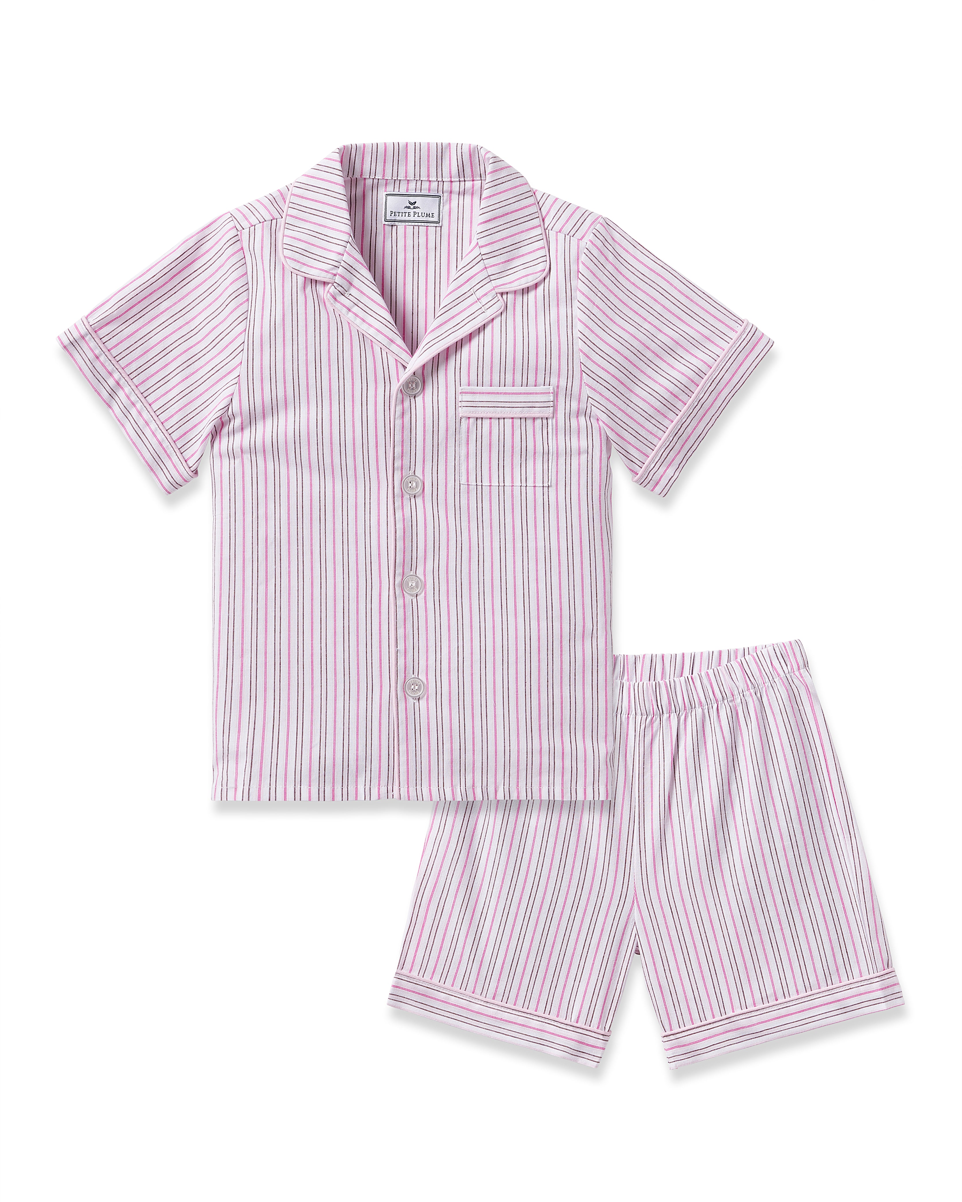 The Kids Twill Short Set in Blush Boulevard by Petite Plume features a luxury cotton, striped short-sleeve button-up shirt with chest pocket and matching shorts. Its pink, white, and blue vertical stripes make it perfect Valentines Day sleepwear.