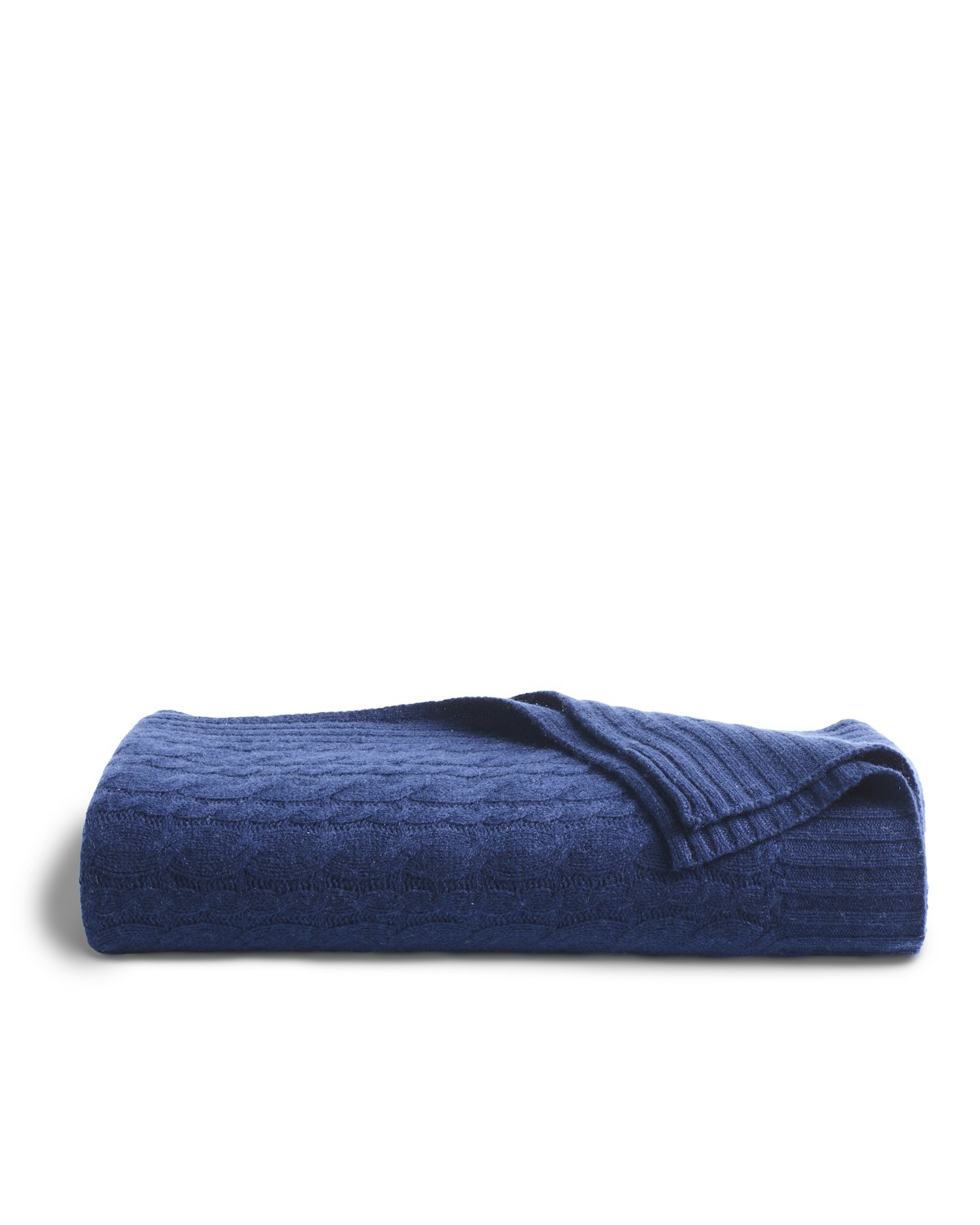 The Cashmere Cable Knit Throw in Navy by Petite Plume is neatly folded on a white background, showcasing its textured pattern and partially revealing the underside. This exquisite cashmere-wool throw adds elegance to any home decor.