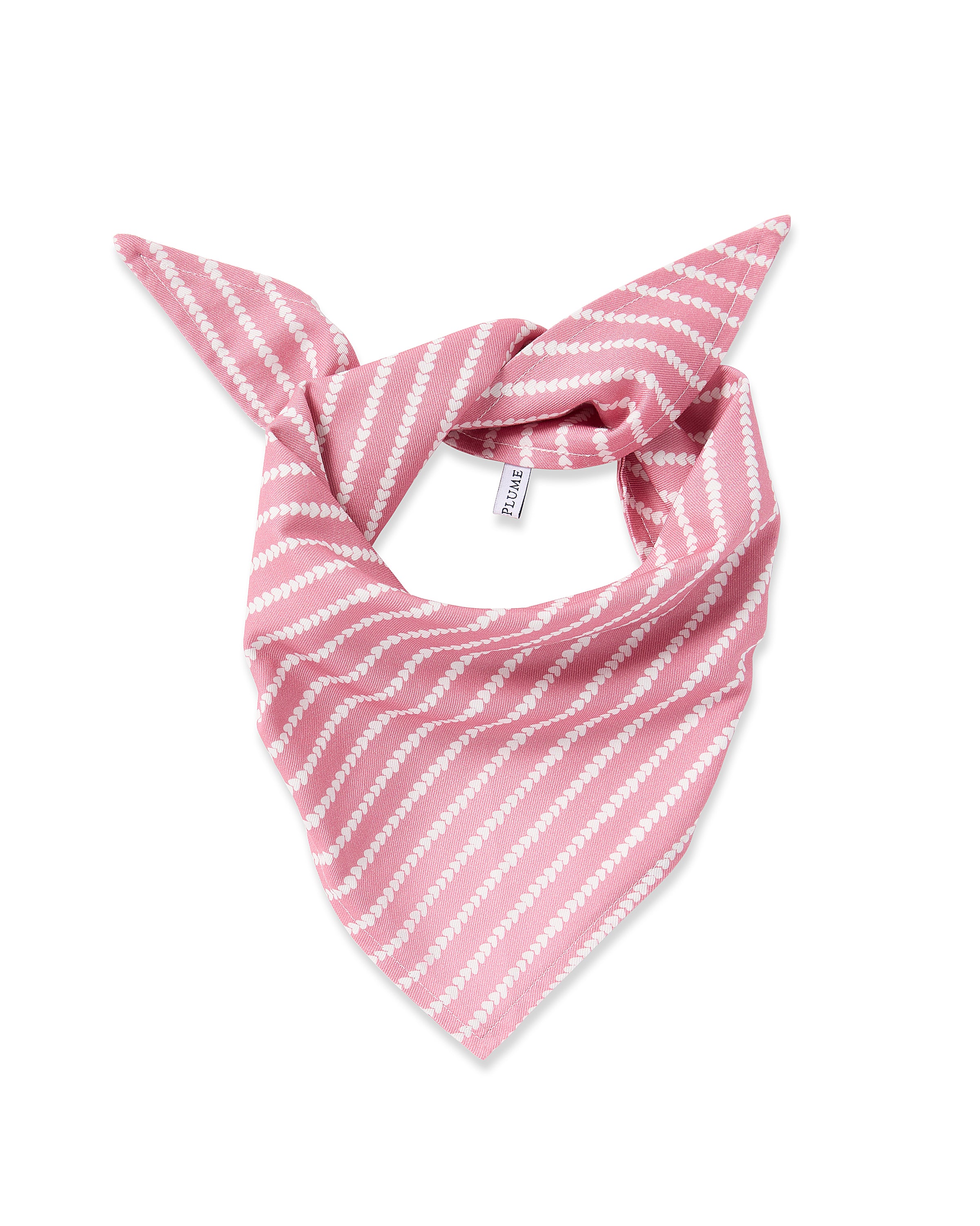 The Twill Dog Bandana in Love Lines features pink fabric with white diagonal stripes, folded into a triangle and knotted at the top, shown on a white background.