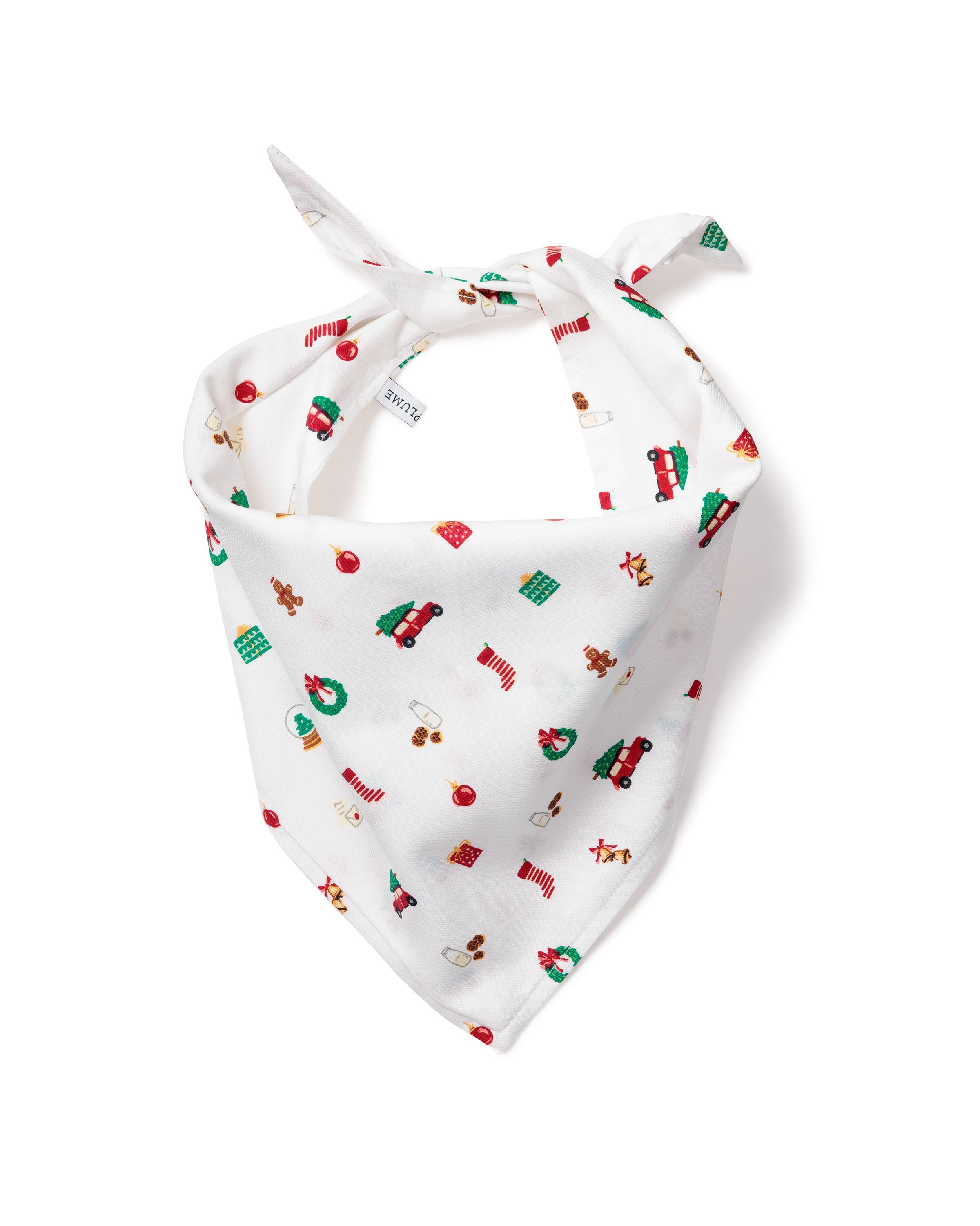 The Twill Dog Bandana in Winter Nostalgia features a white background with Christmas-themed prints like Santa, gingerbread men, presents, trees, stockings, and ornaments. It’s tied at the top and displayed on a plain white surface.